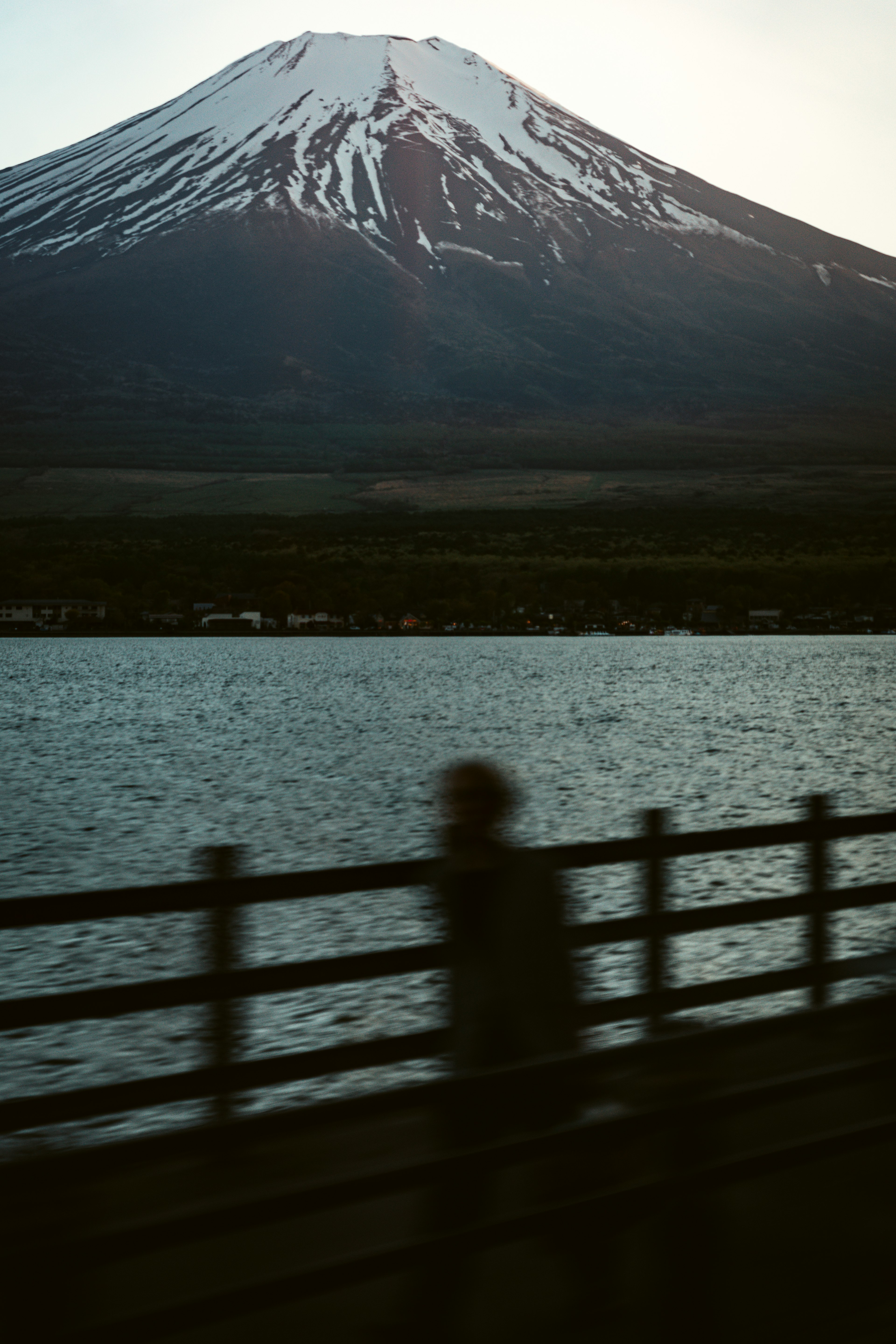 Blurred silhouette of a person with Mount Fuji and a lake in the background