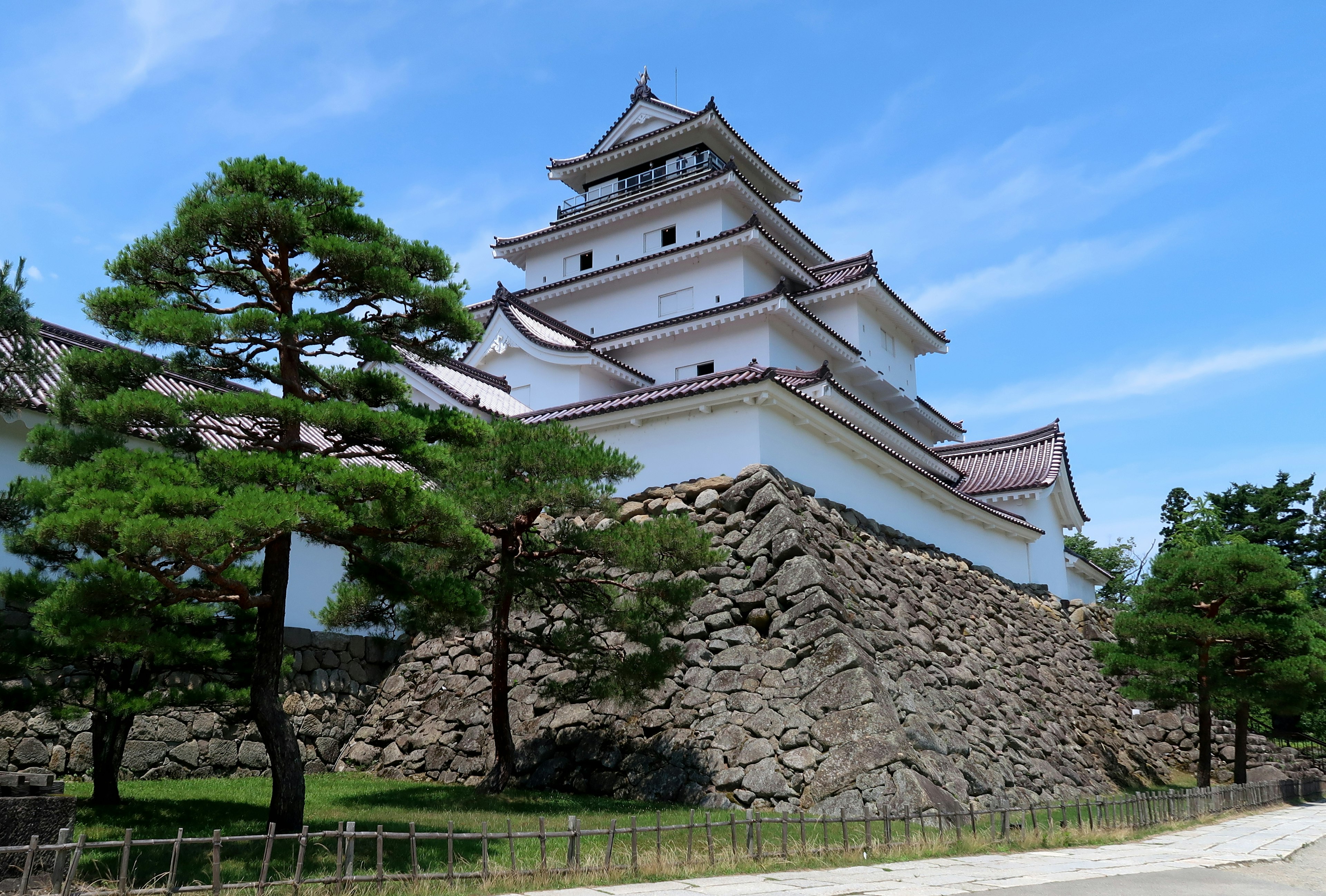 Vista de un castillo japonés con paredes blancas y base de piedra