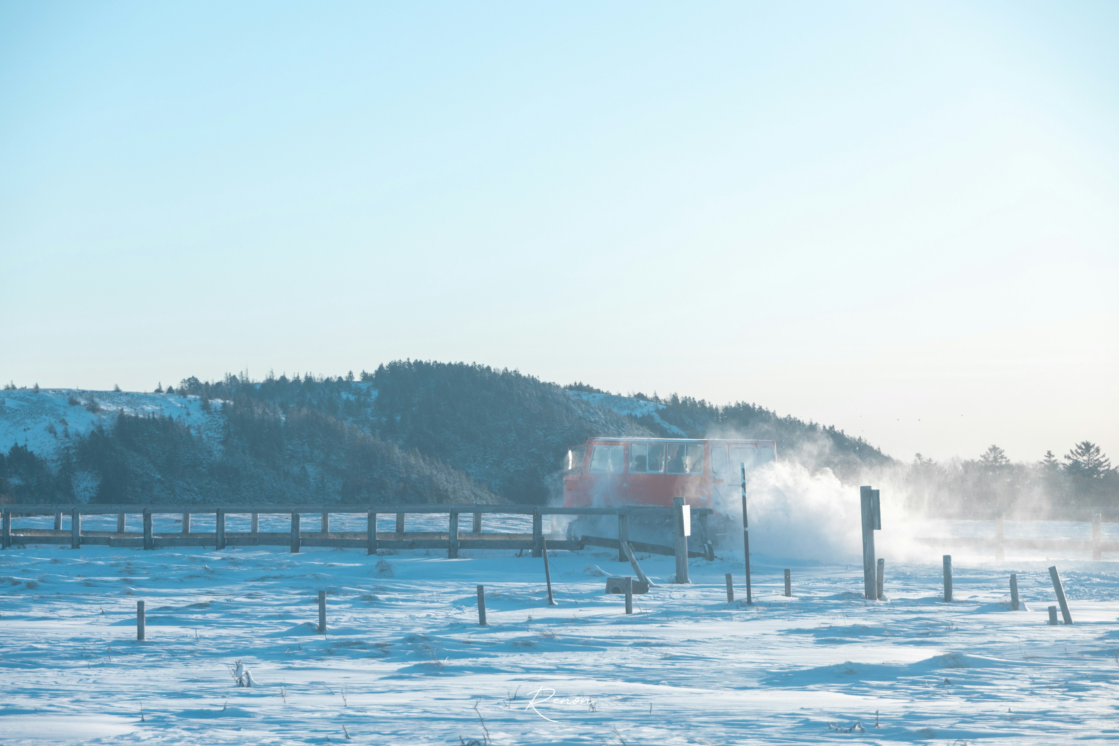 Train traveling through a snowy landscape under a blue sky