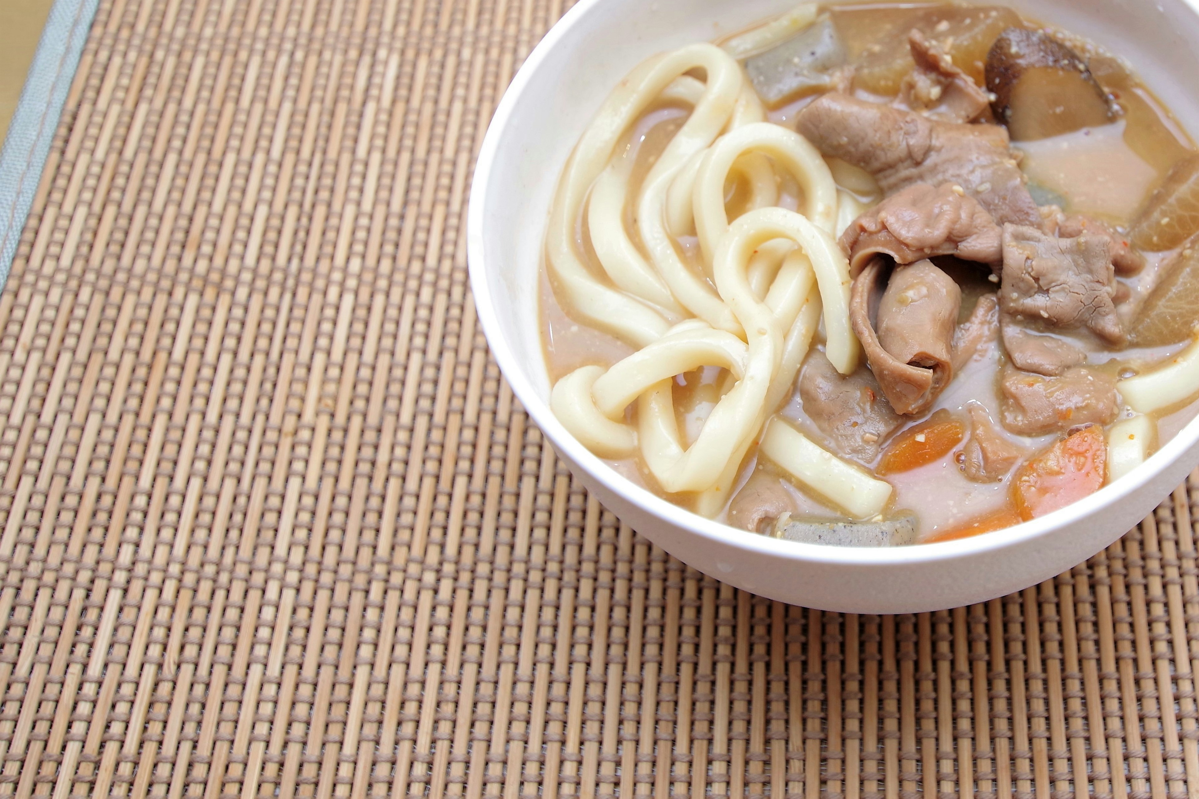 Schüssel mit Udon-Nudeln und Fleisch in Brühe