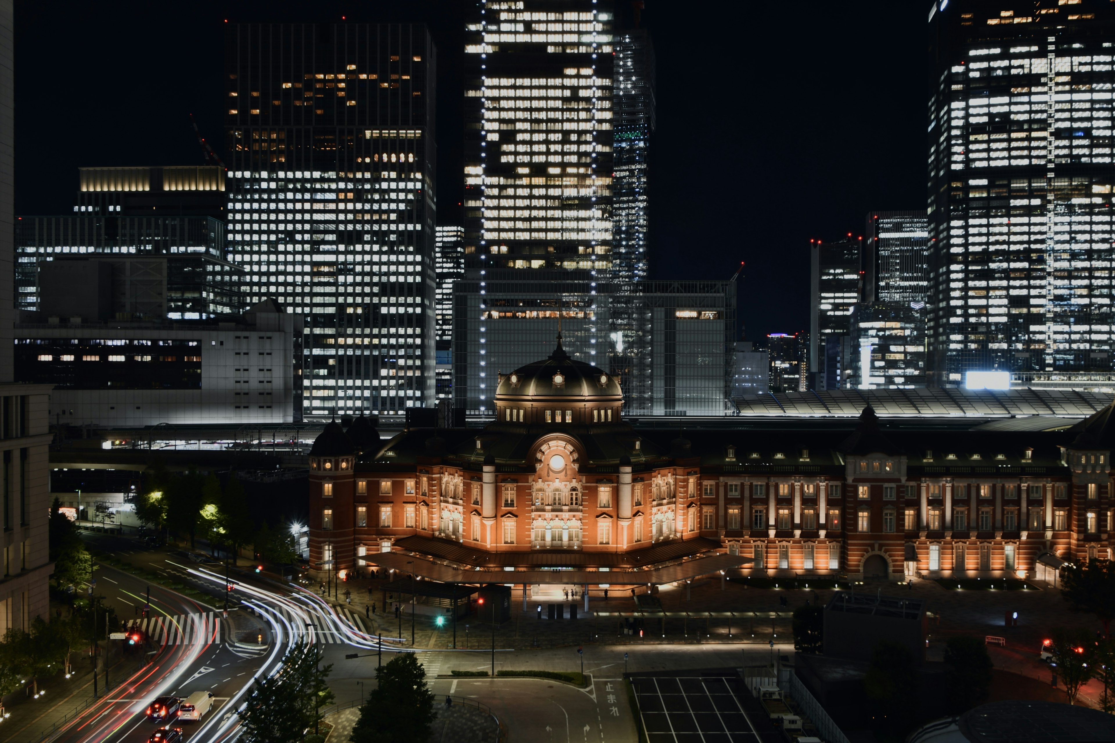 Nachtansicht des Tokyo Bahnhofs beleuchtet mit modernen Wolkenkratzern im Hintergrund