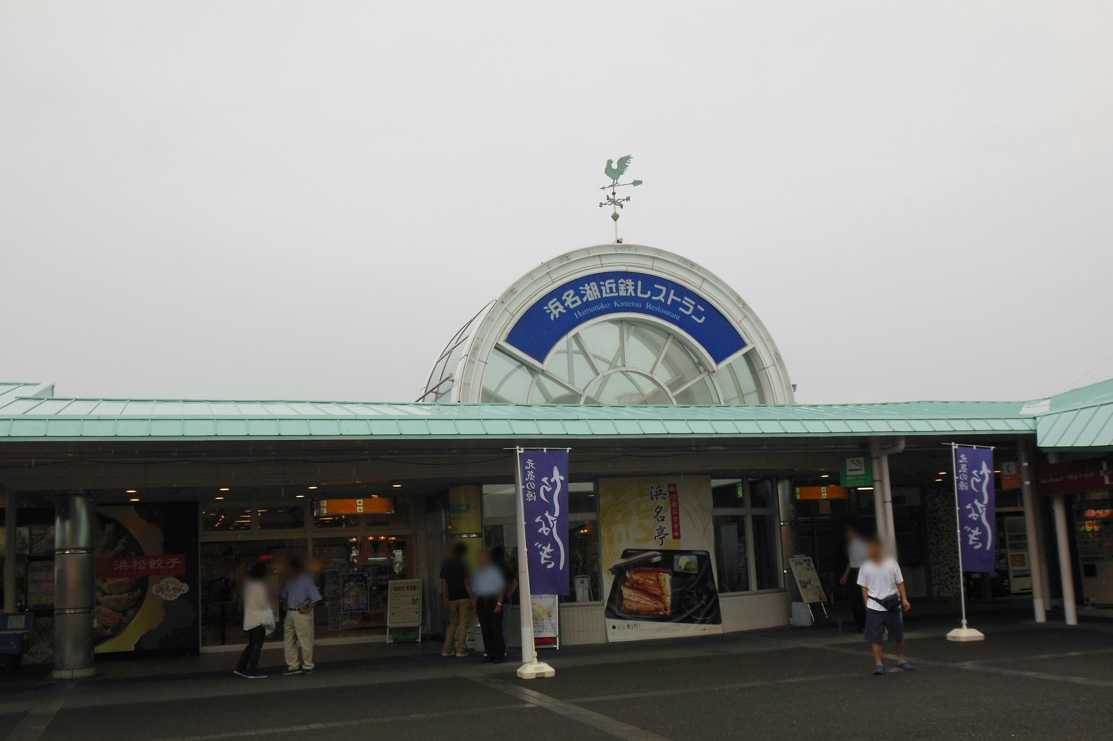 Exterior view of a station with a blue sign and people walking