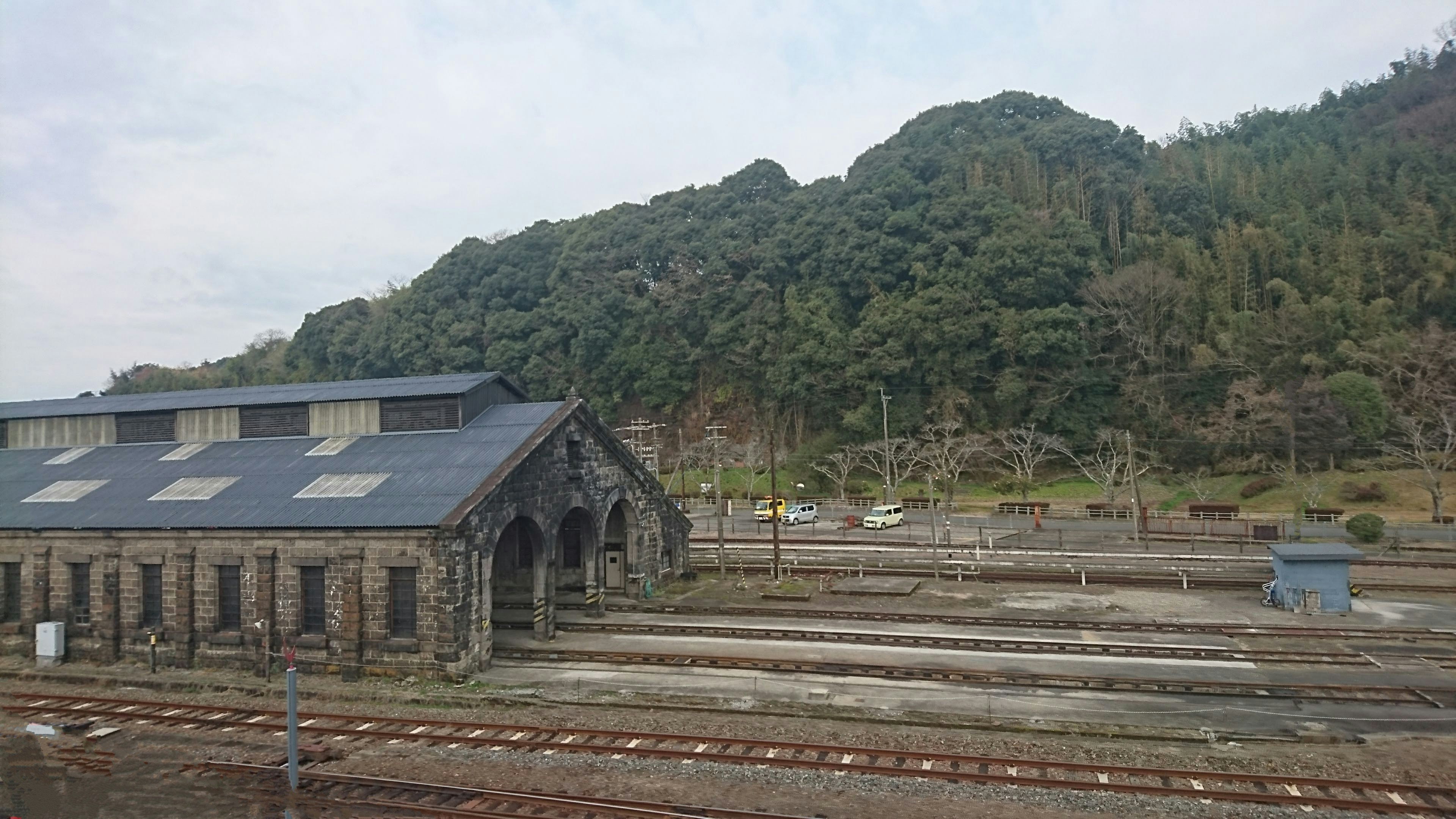 Ancien bâtiment de gare avec des voies et de la verdure en arrière-plan