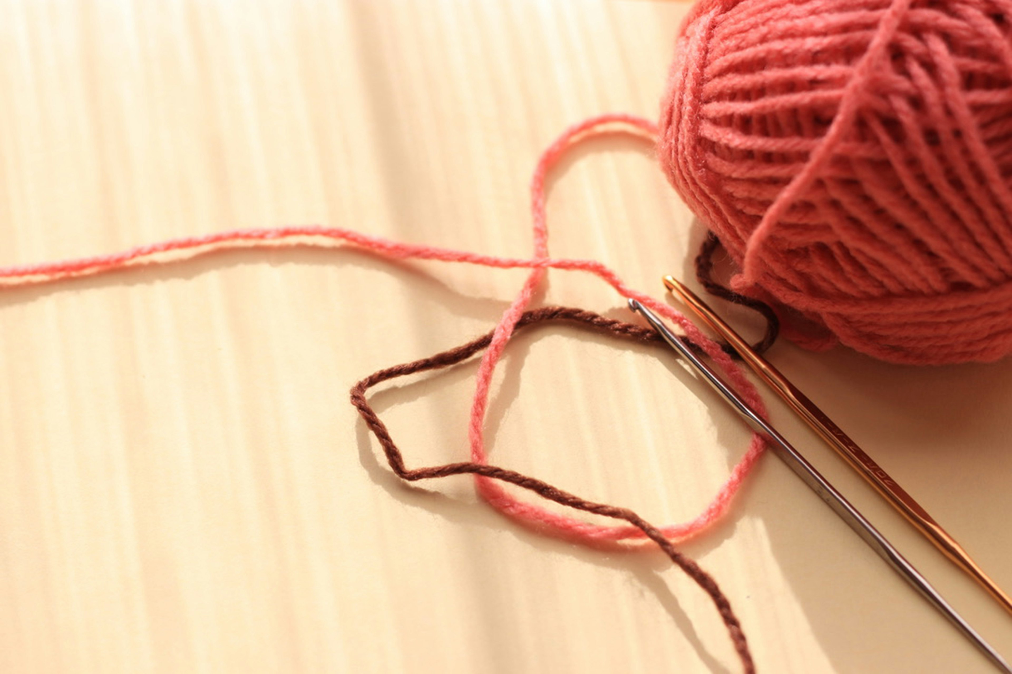 Image de fil à tricoter rose et d'aiguilles à tricoter sur une surface en bois