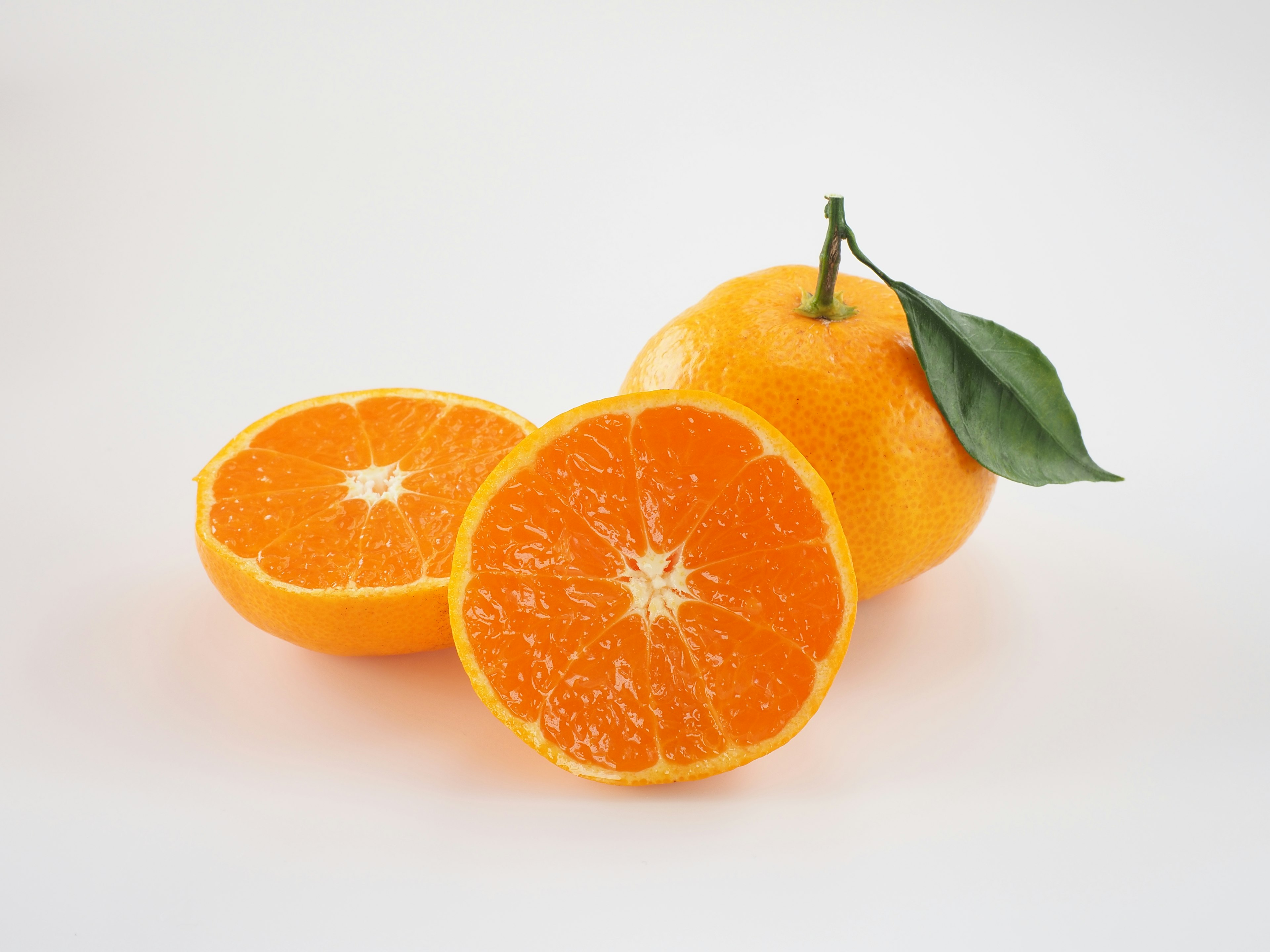 A whole orange with a sliced half showcasing bright orange flesh