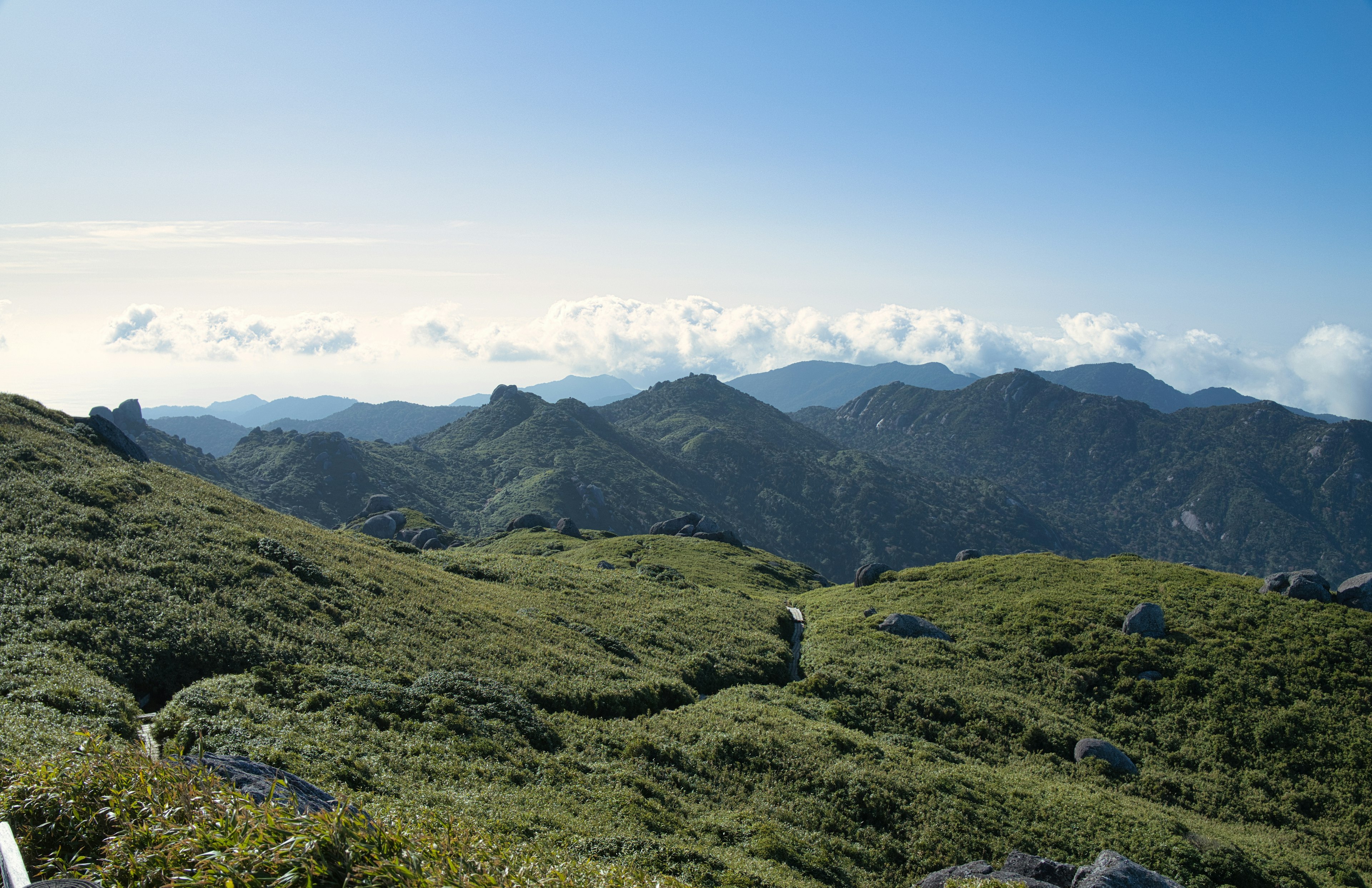 Scenic view of mountains and blue sky with lush green fields