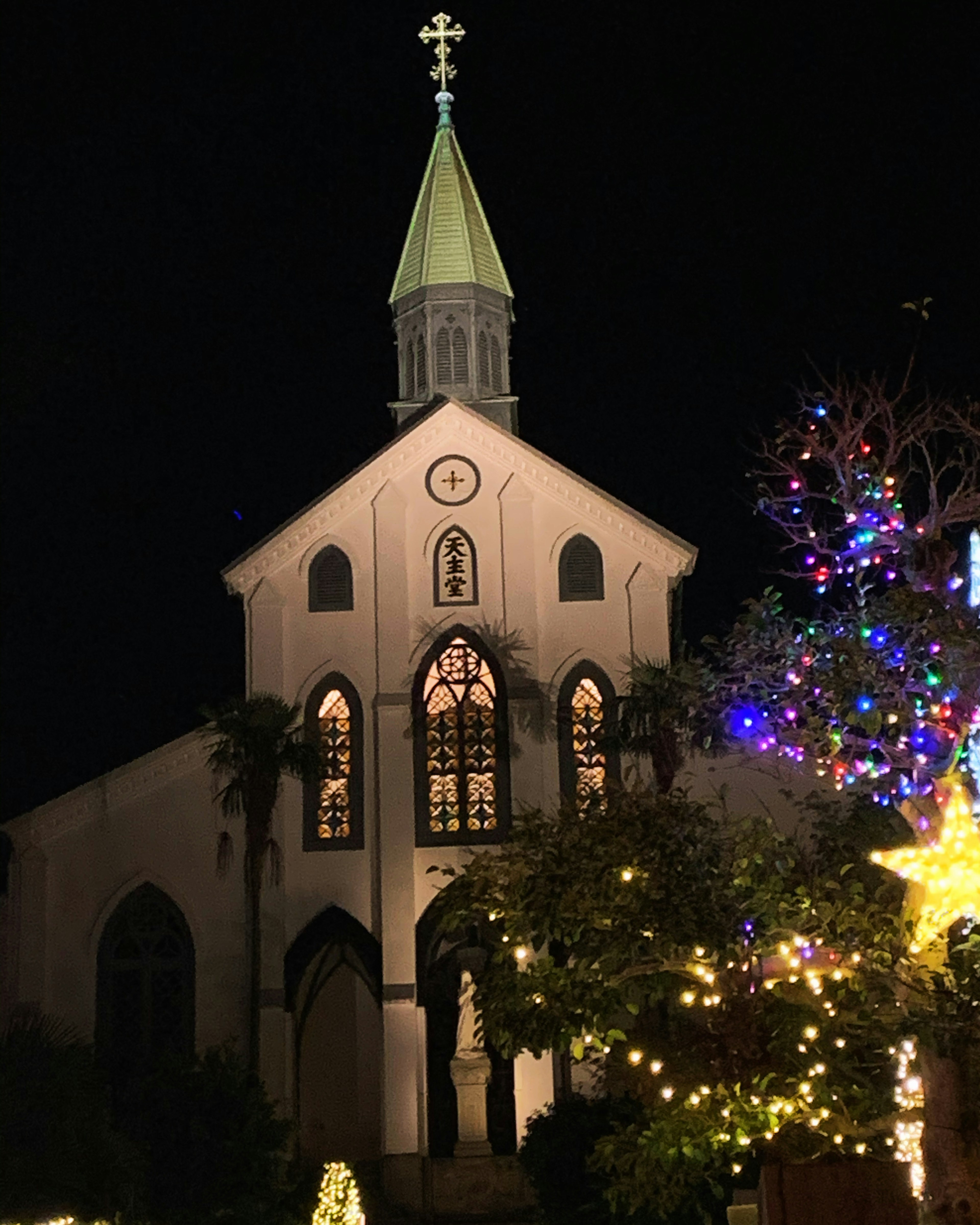 Exterior de una iglesia por la noche con un árbol de Navidad bellamente iluminado