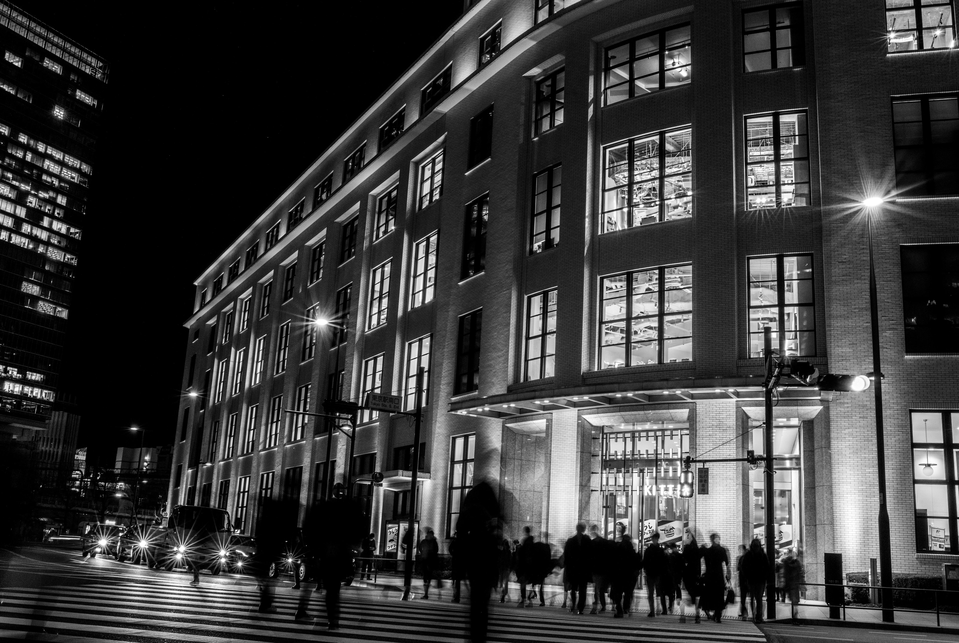 Bâtiment moderne dans une scène nocturne urbaine avec des silhouettes de personnes