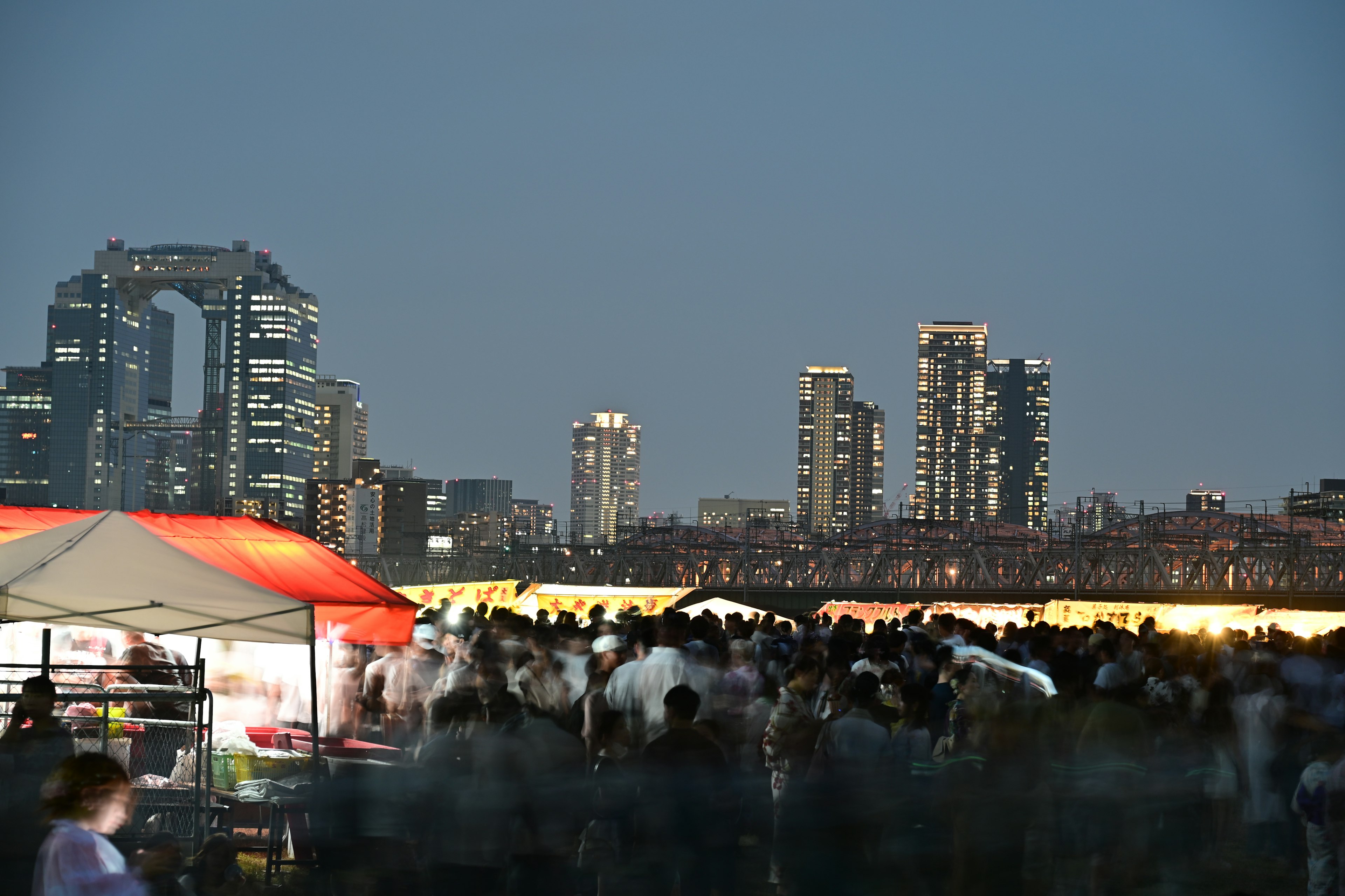 Outdoor event with a crowd and city skyline at night