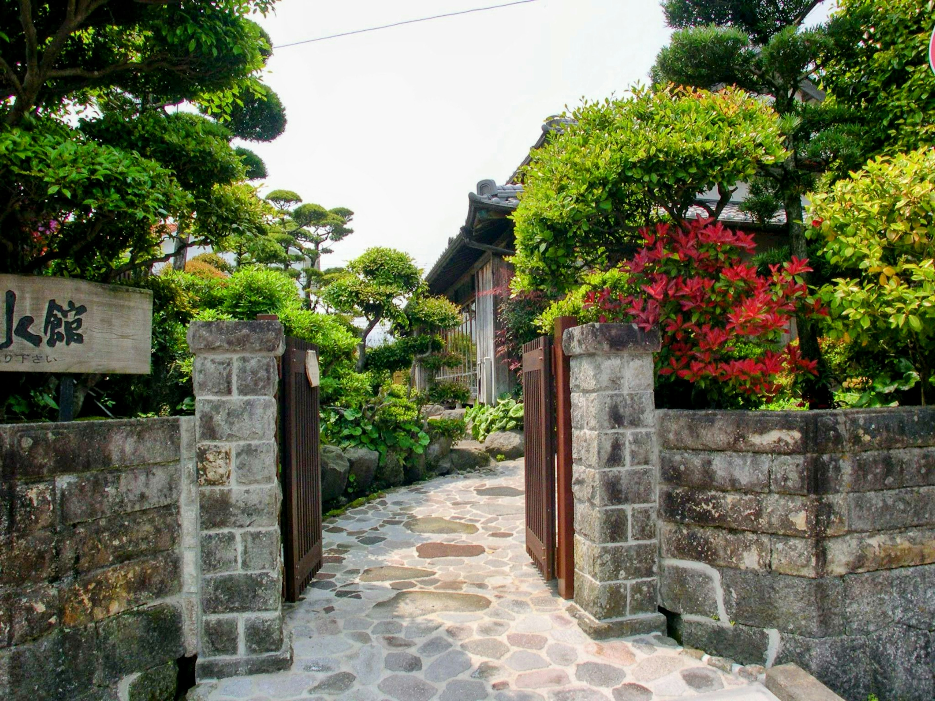 Entrée d'une maison japonaise traditionnelle avec un beau jardin présentant des murs en pierre et des portails en bois