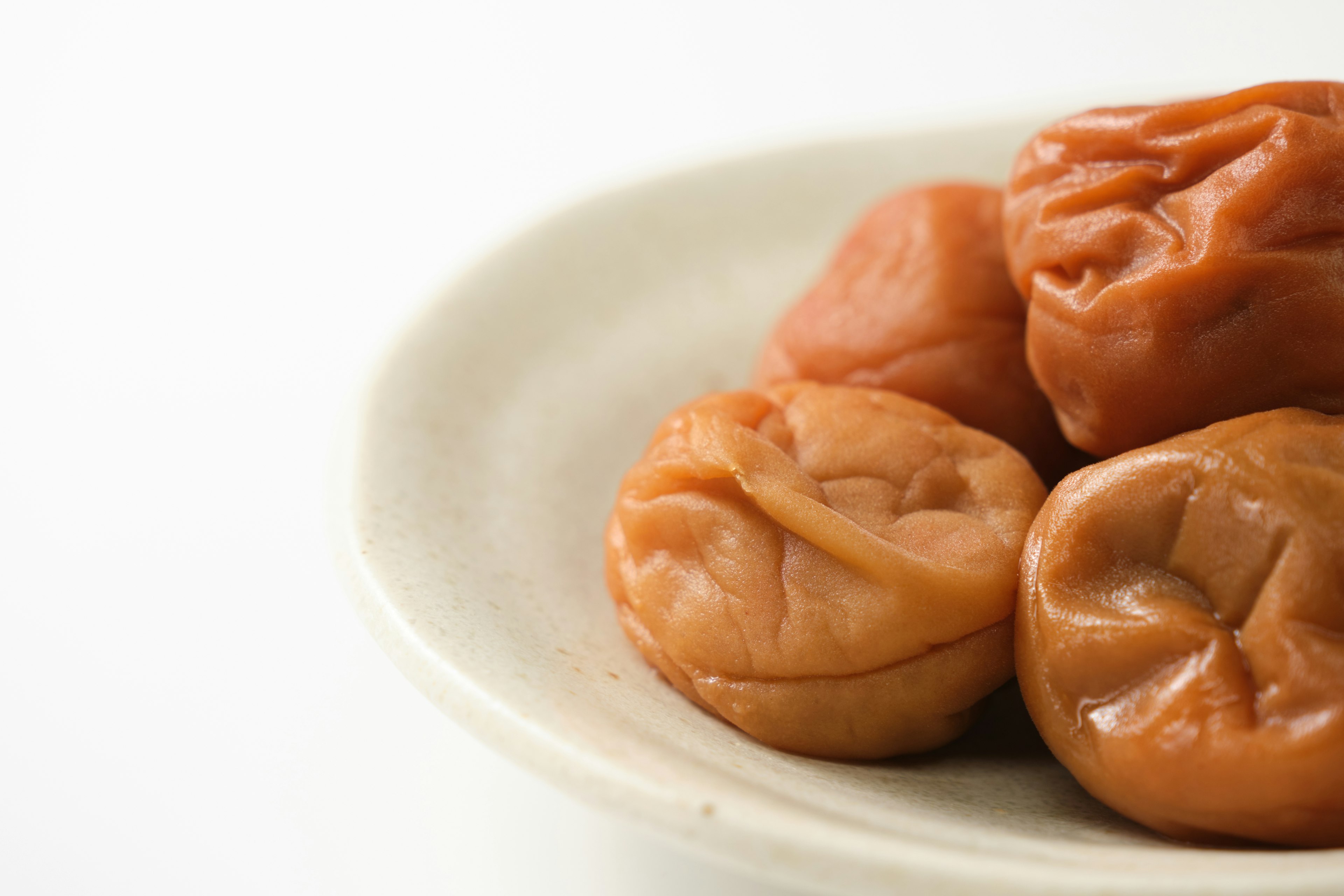 A cluster of pickled plums on a white plate