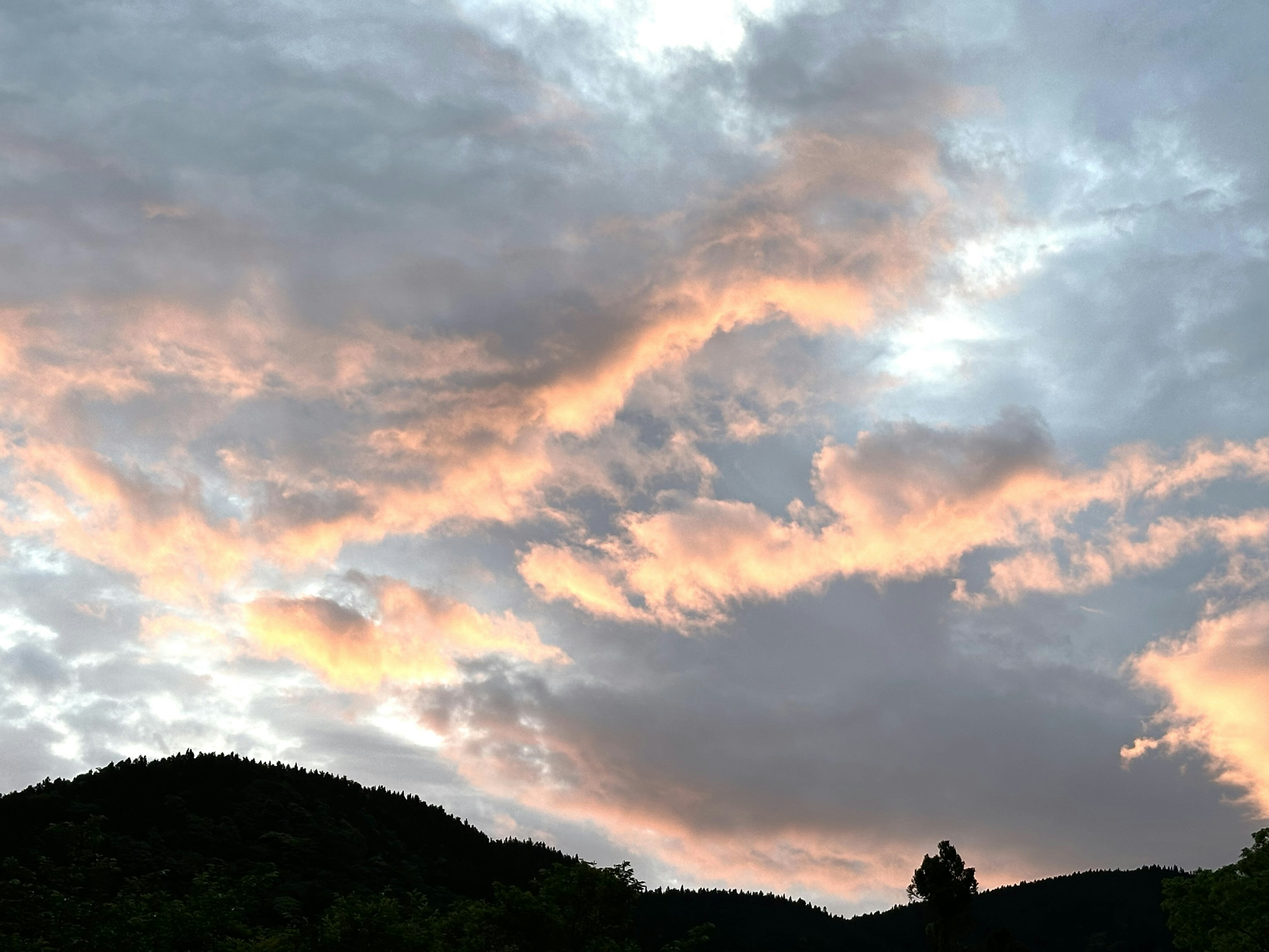 Cielo de atardecer con nubes y silueta de montaña