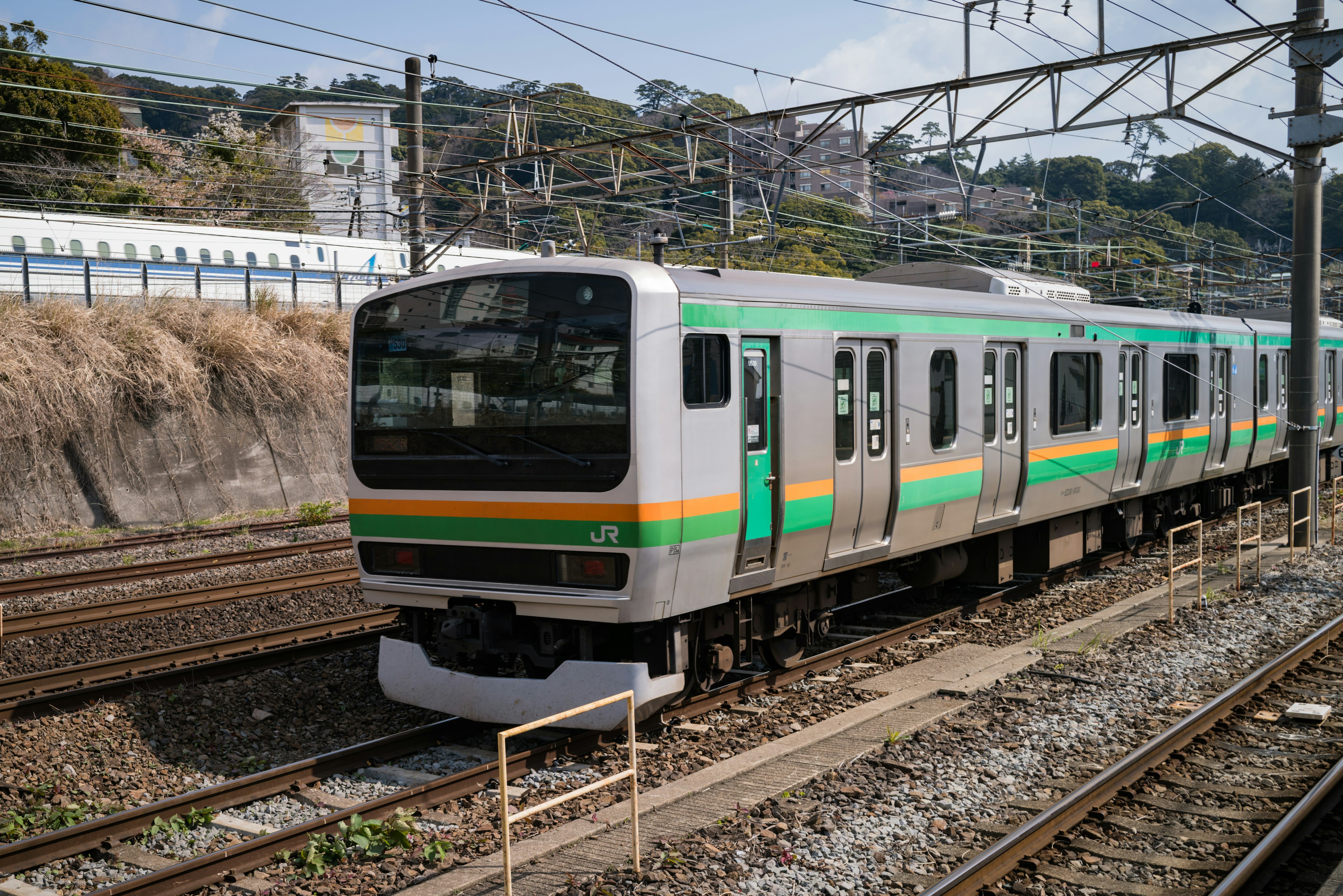 Kereta dengan garis hijau dan kuning yang diparkir di rel