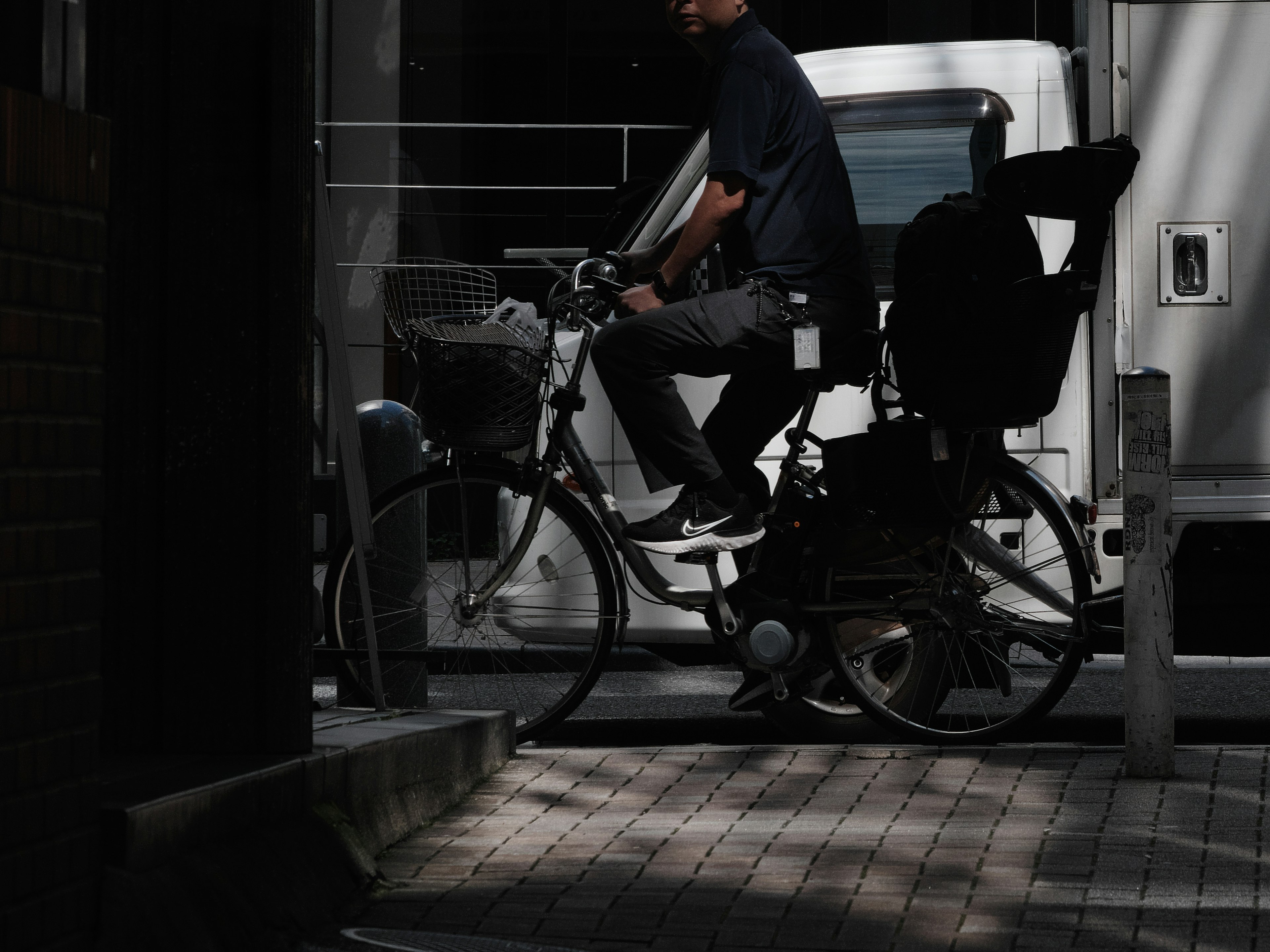 Man riding a bicycle with a white vehicle in the background