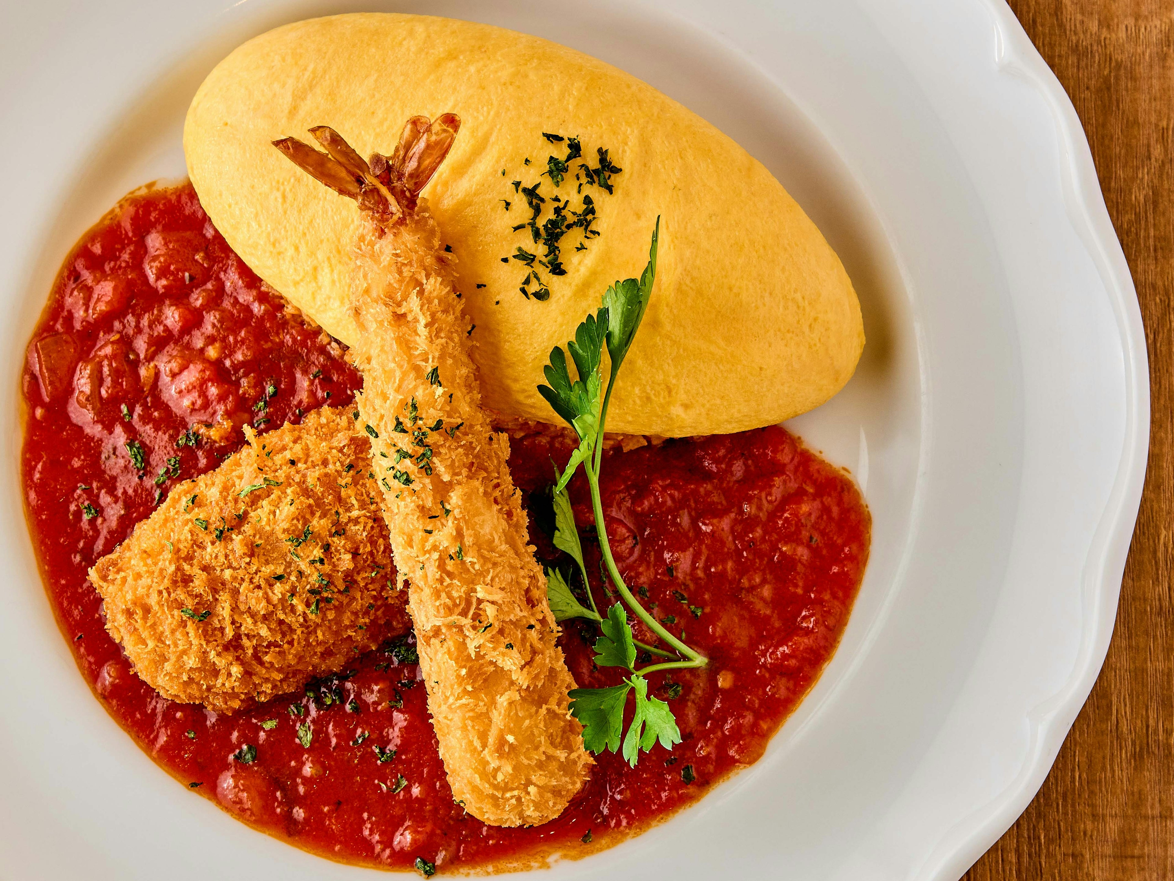 Omelet on a plate with shrimp and croquette in tomato sauce