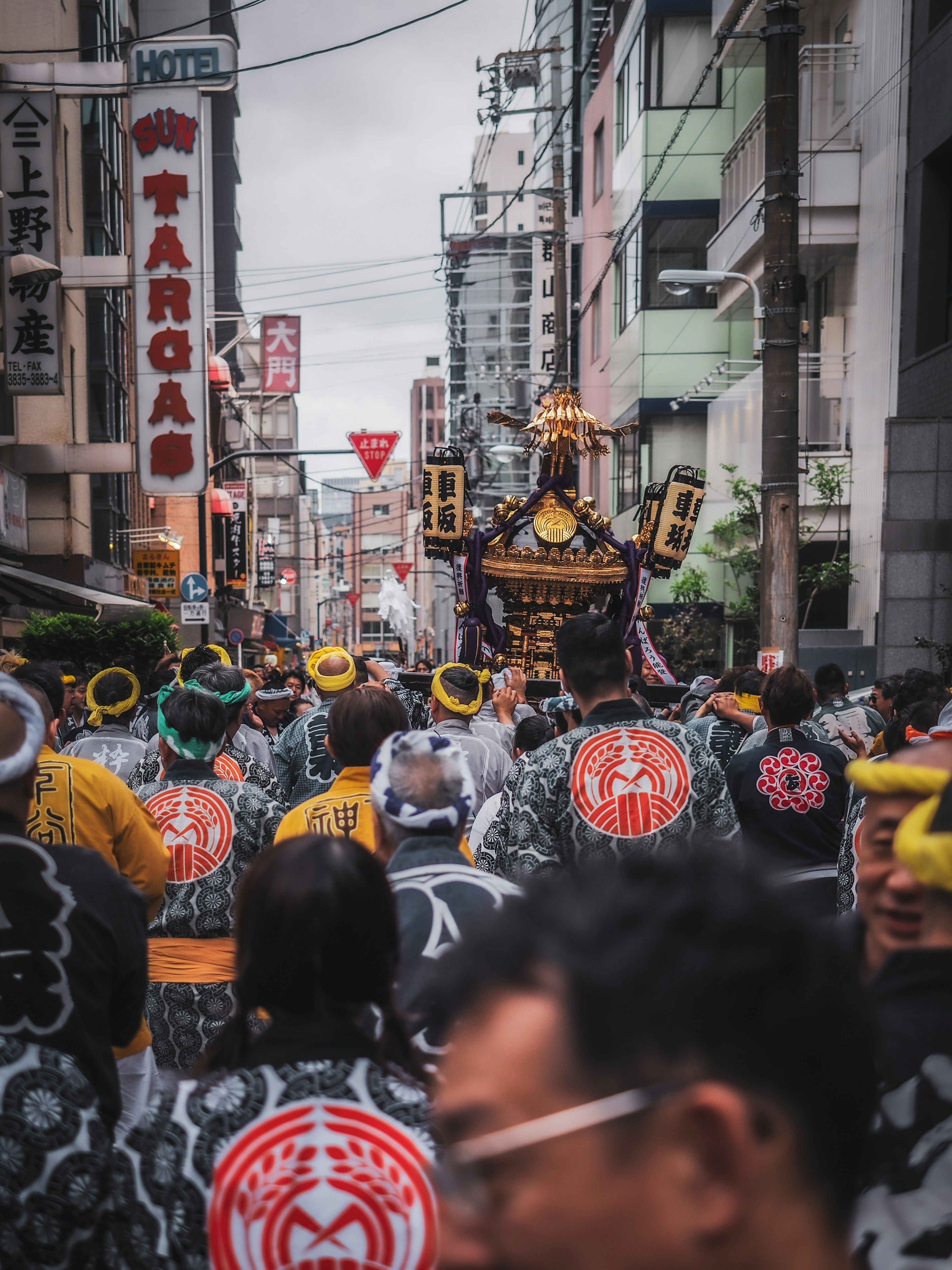 Procession featuring a portable shrine with people in traditional attire in a city street