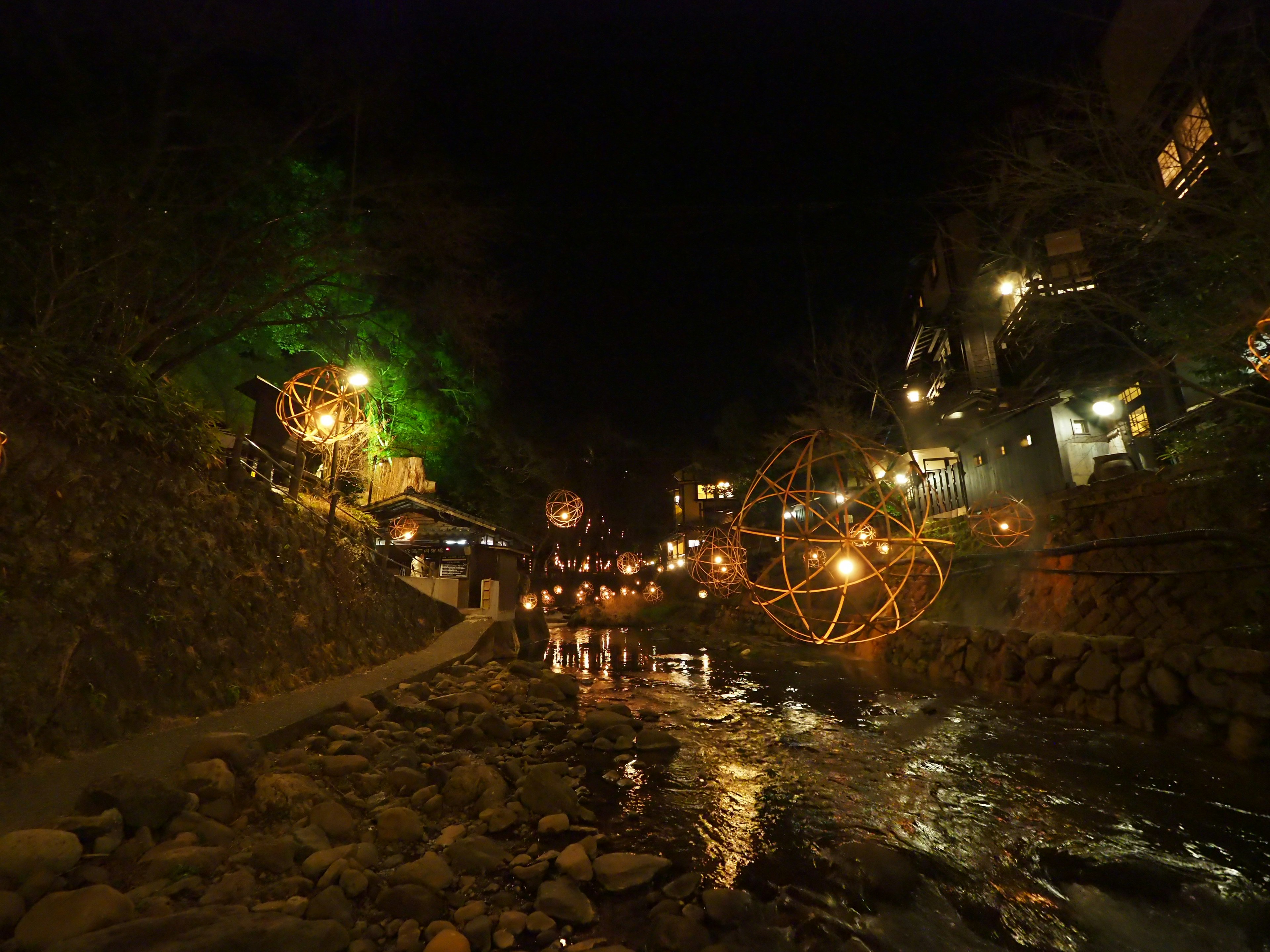 Vue nocturne pittoresque d'une rivière illuminée par des lumières chaudes et des structures sphériques décoratives