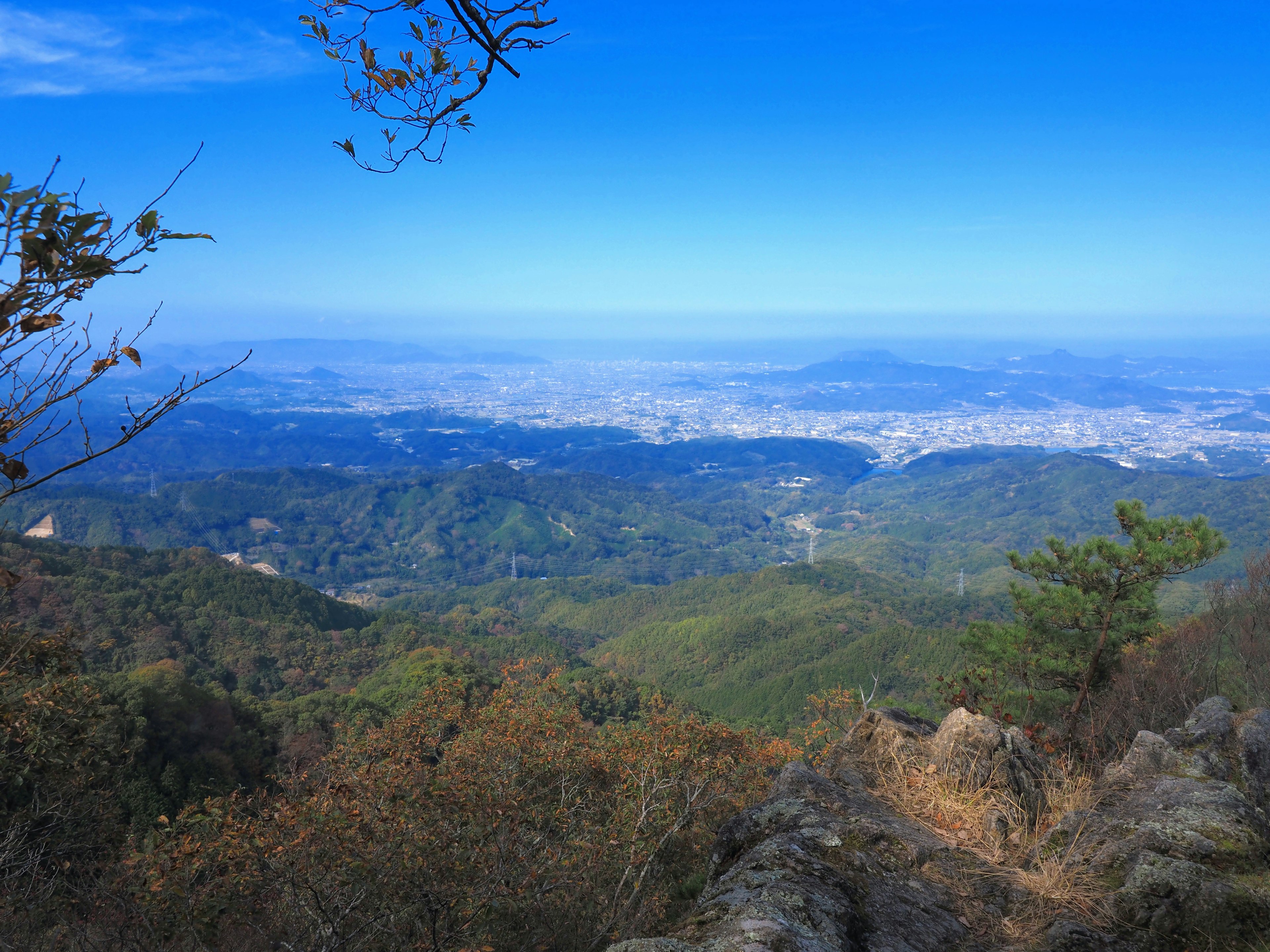 Pemandangan indah dari puncak gunung dengan bukit hijau dan kota yang luas