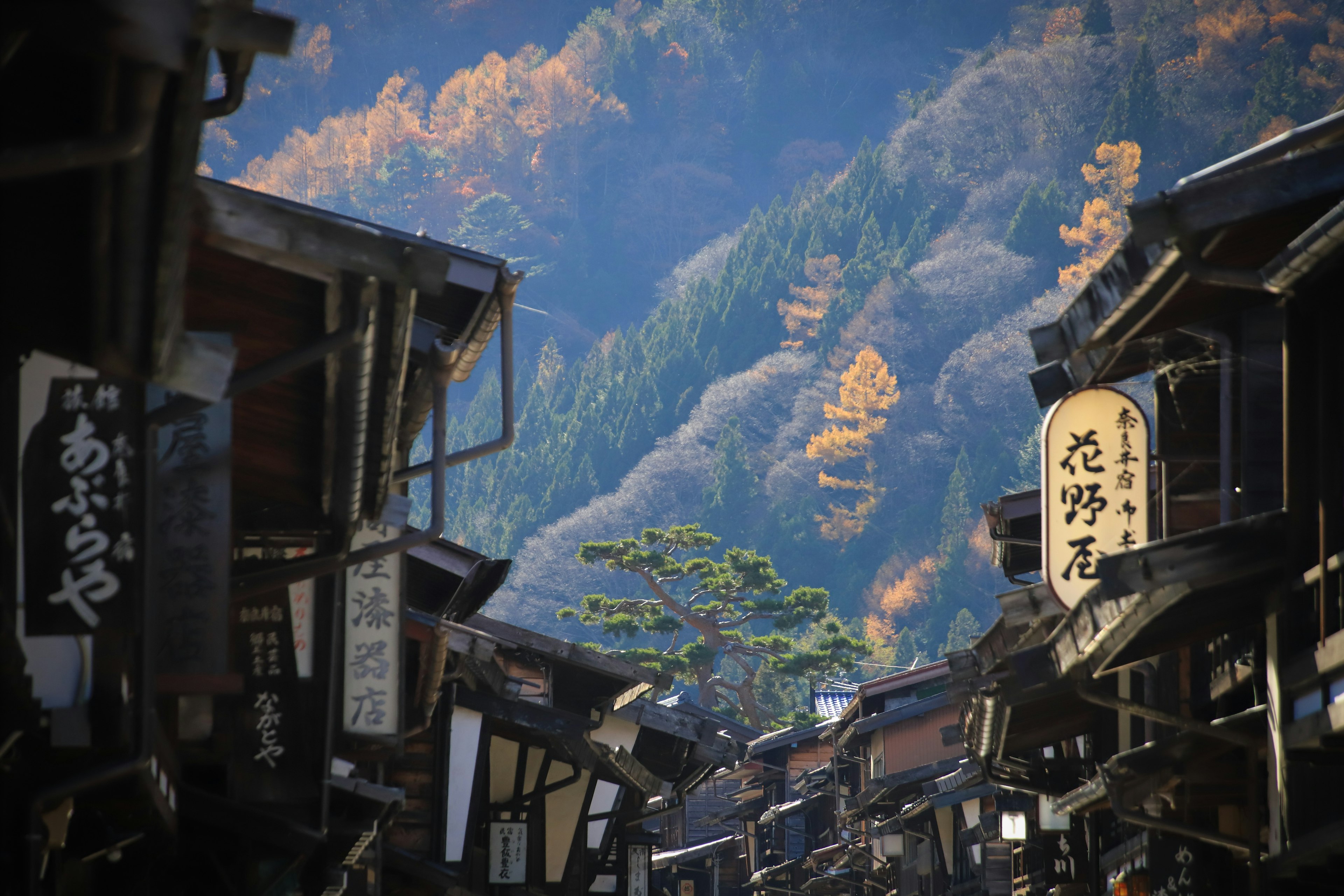 Historic street lined with traditional signs and surrounded by mountains