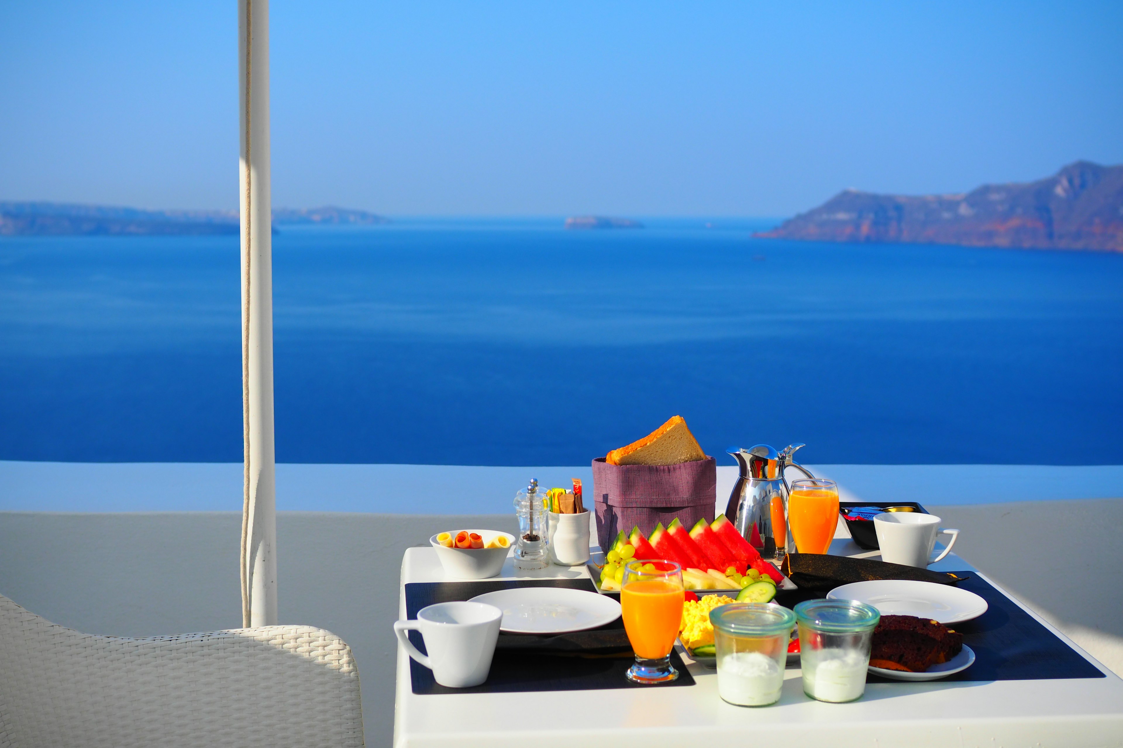 Tavolo da colazione su una terrazza con vista sul mare blu frutta fresca e yogurt disposti