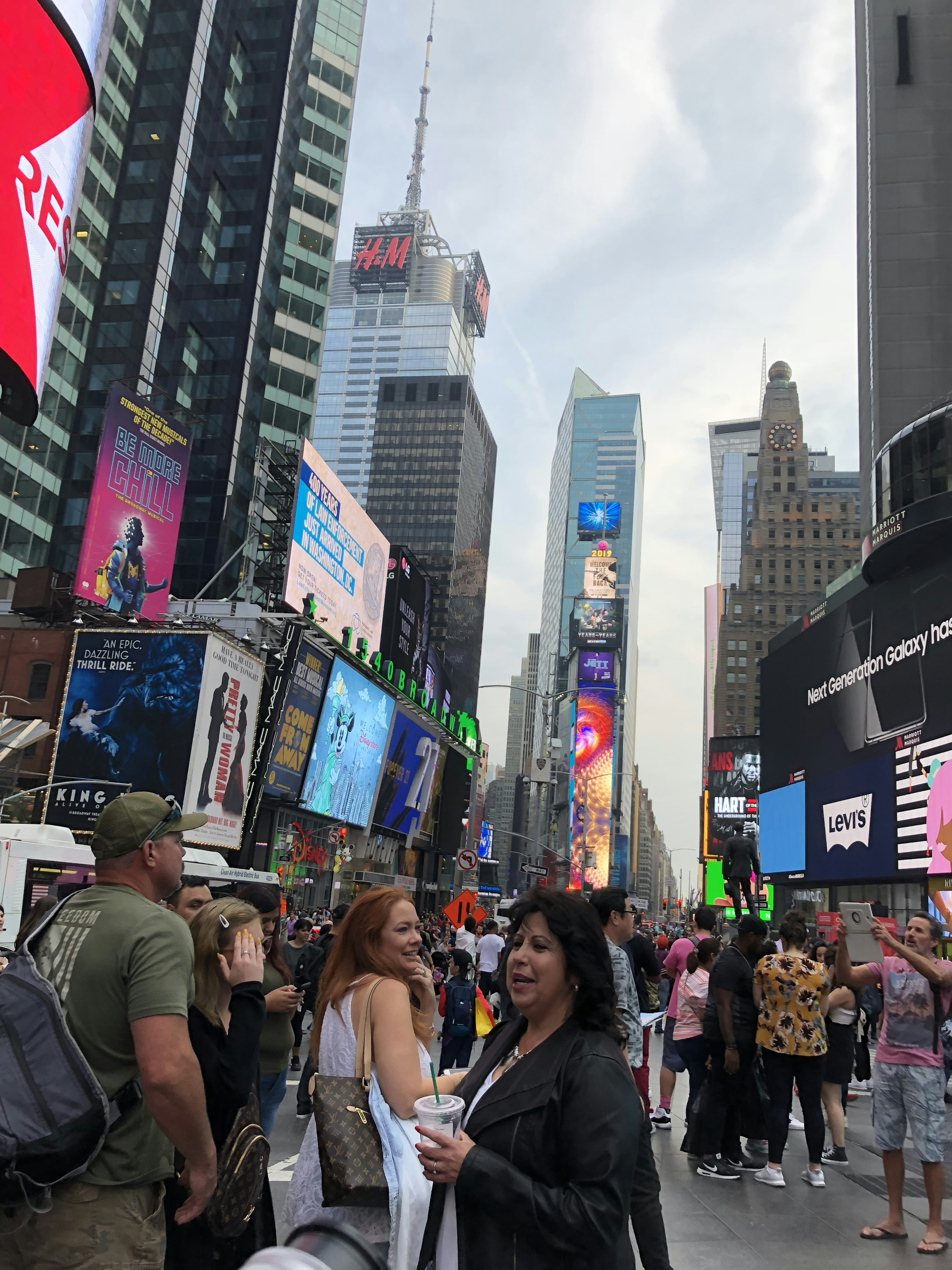 Pemandangan ramai di Times Square dengan orang-orang berkumpul dan iklan yang cerah