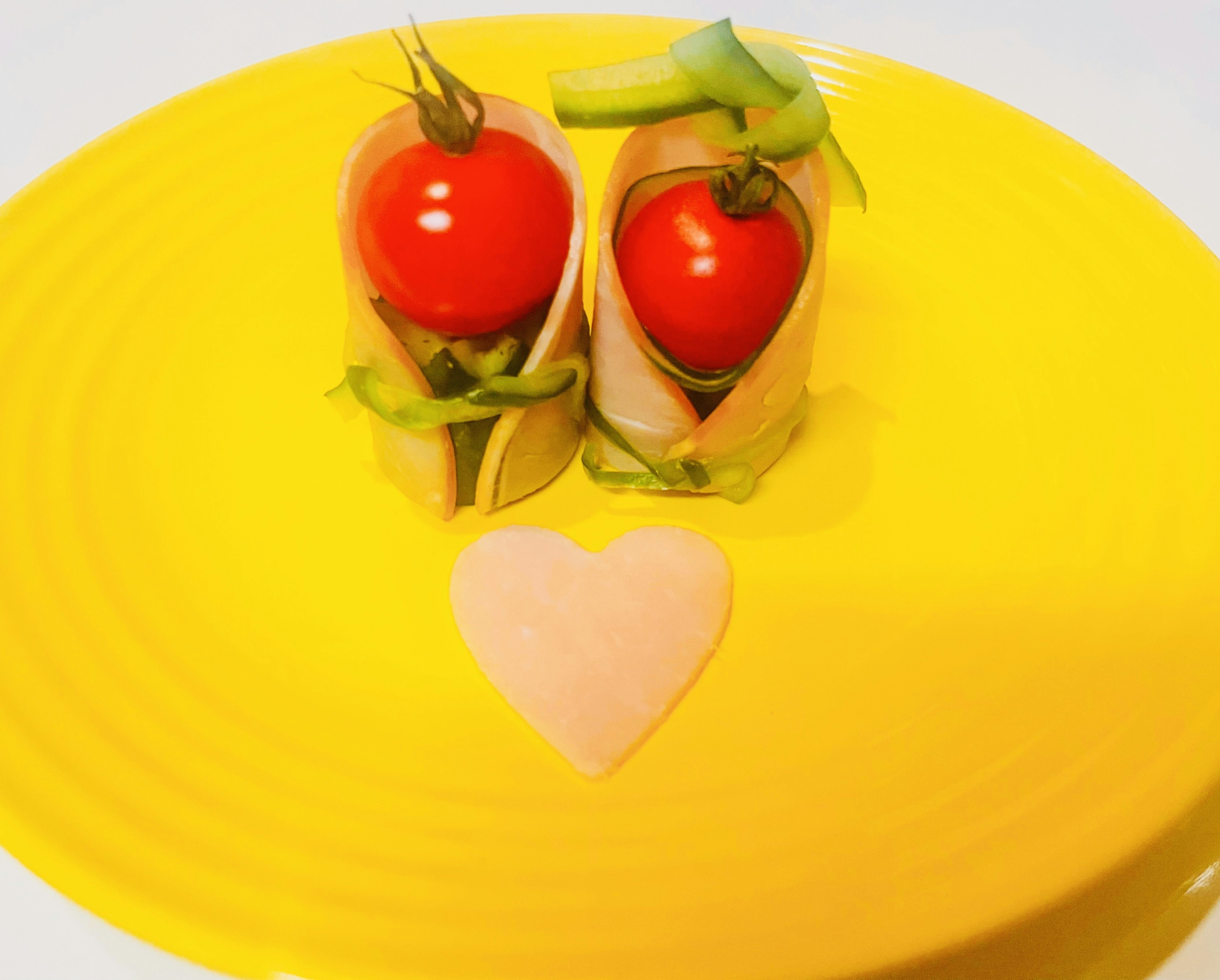 Rote Tomaten in grün auf einem gelben Teller mit einem herzförmigen Lebensmittel