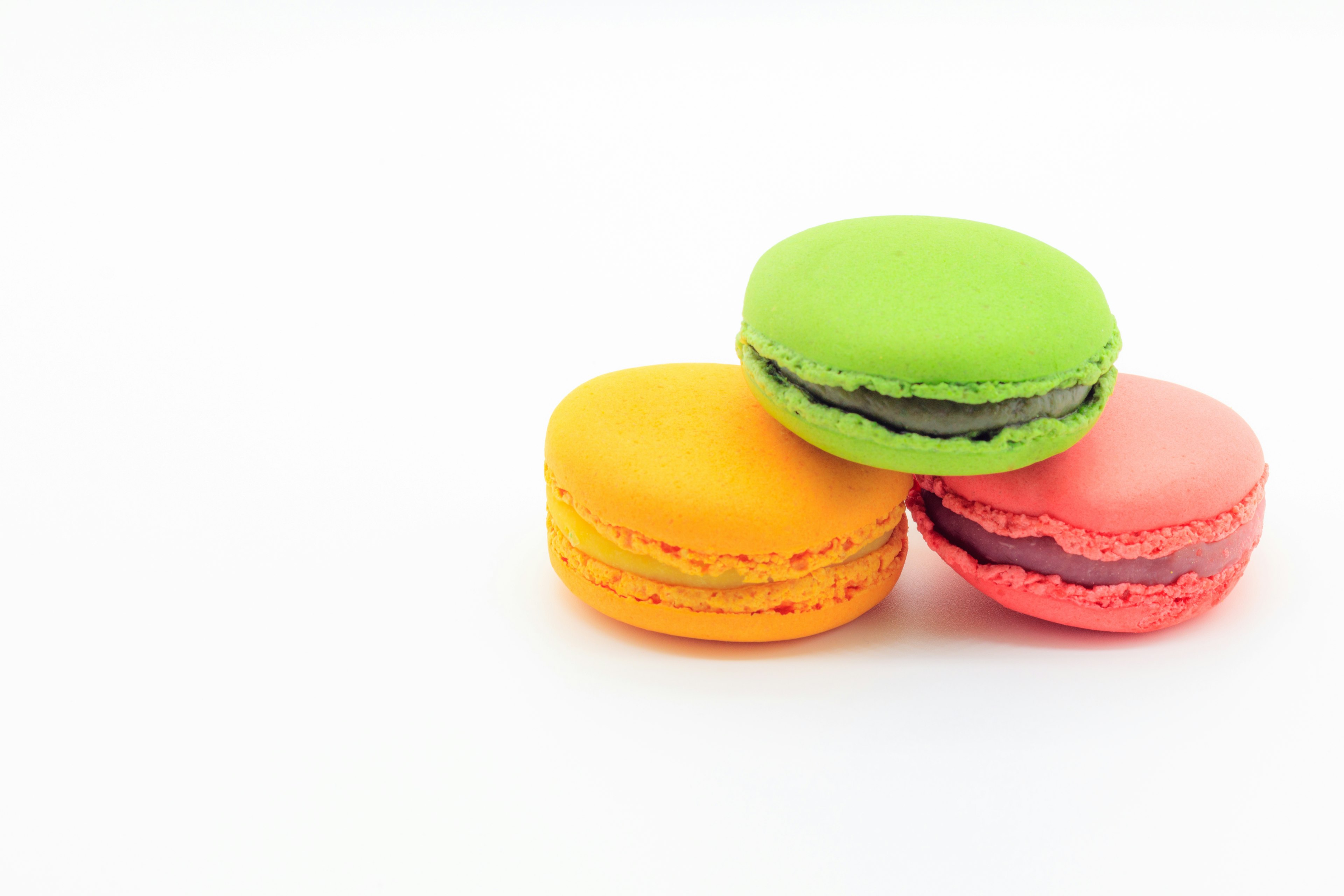 Buntes Set von Macarons mit grünen, orangefarbenen und rosa Macarons