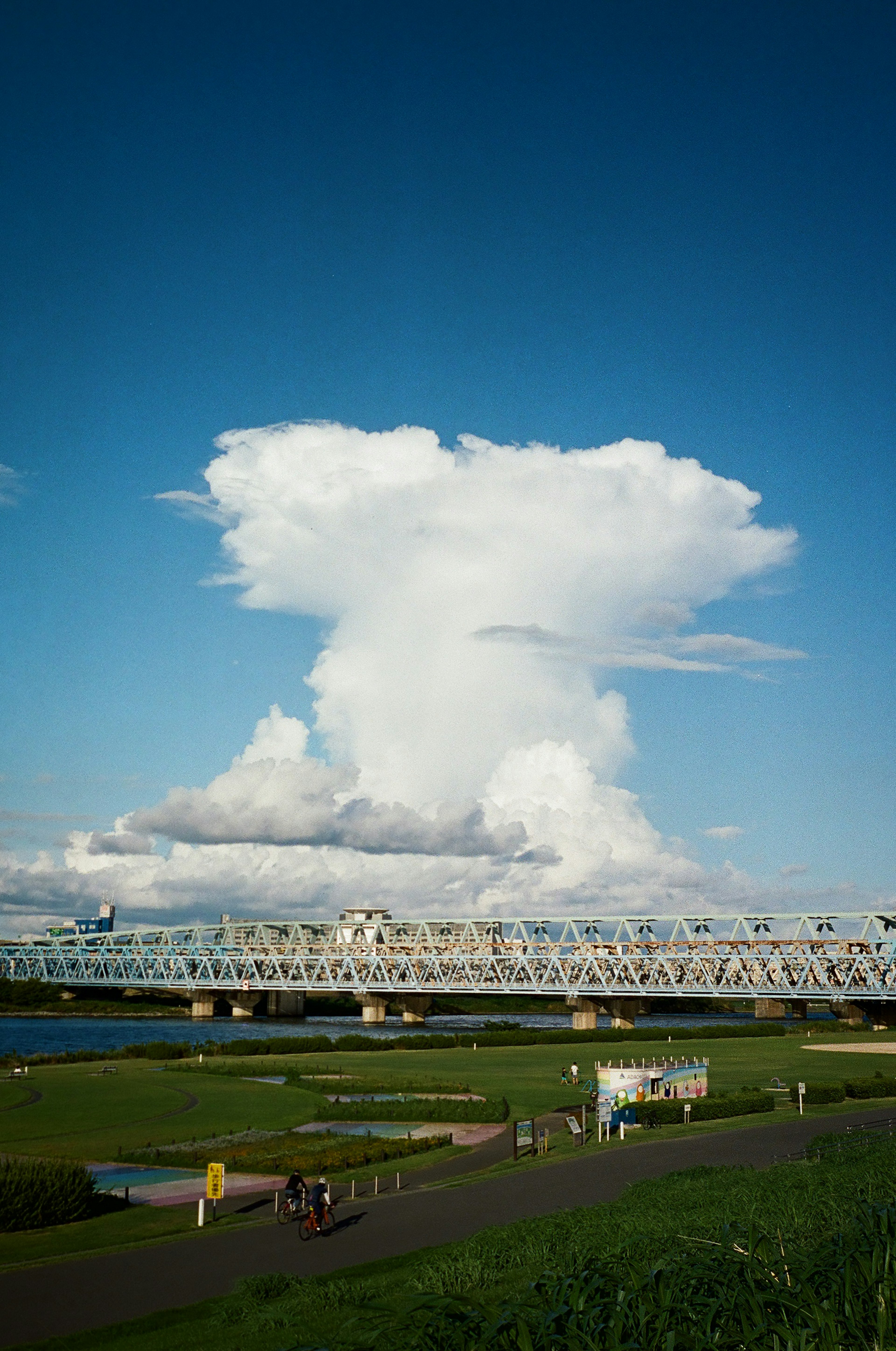 Una gran nube cumulonimbus bajo un cielo azul con un puente en primer plano