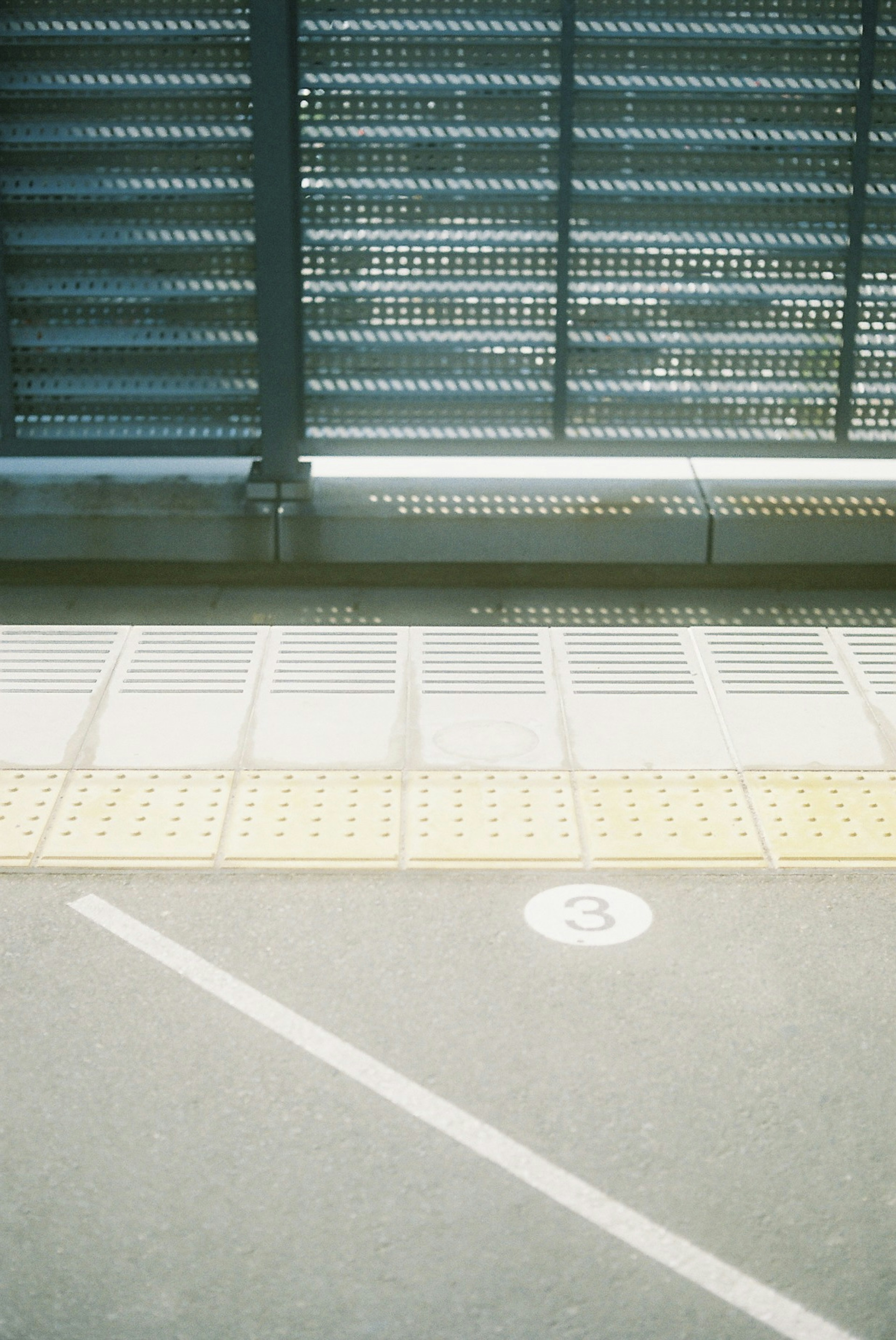 Part of a train platform with metal panels and tactile paving