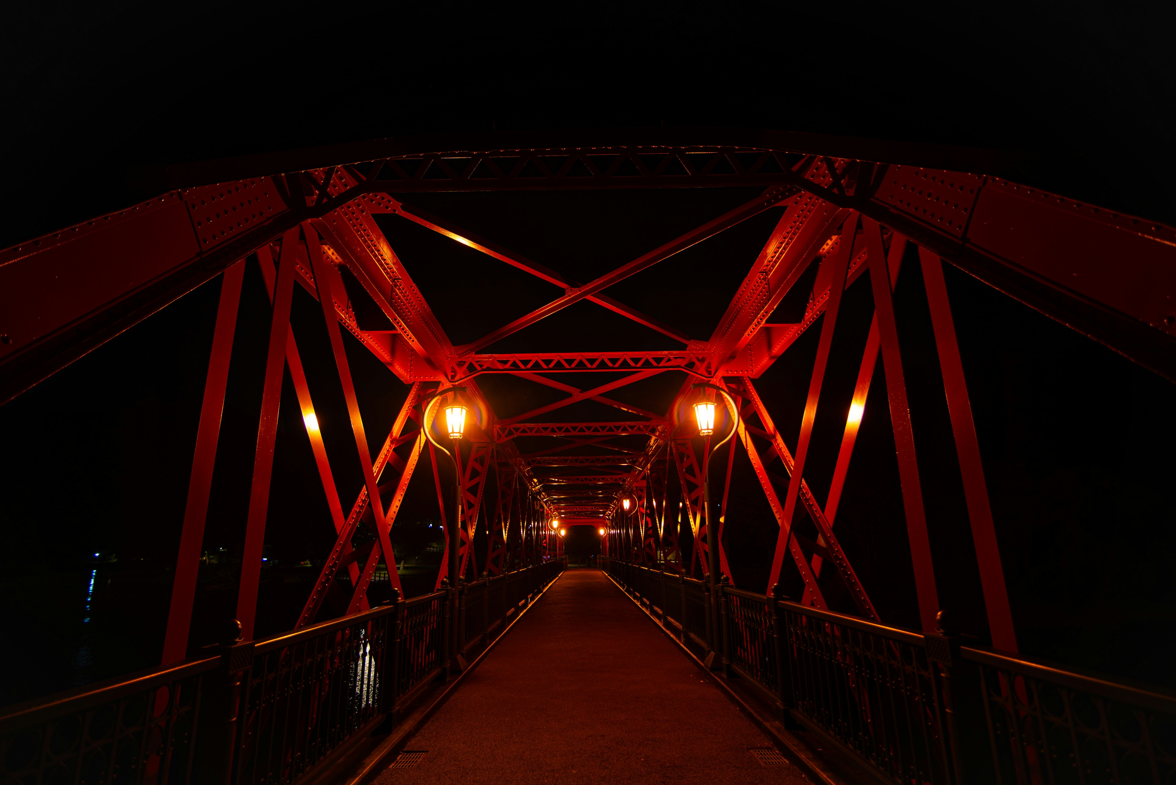 Vista notturna di un ponte rosso con struttura intricata e illuminazione