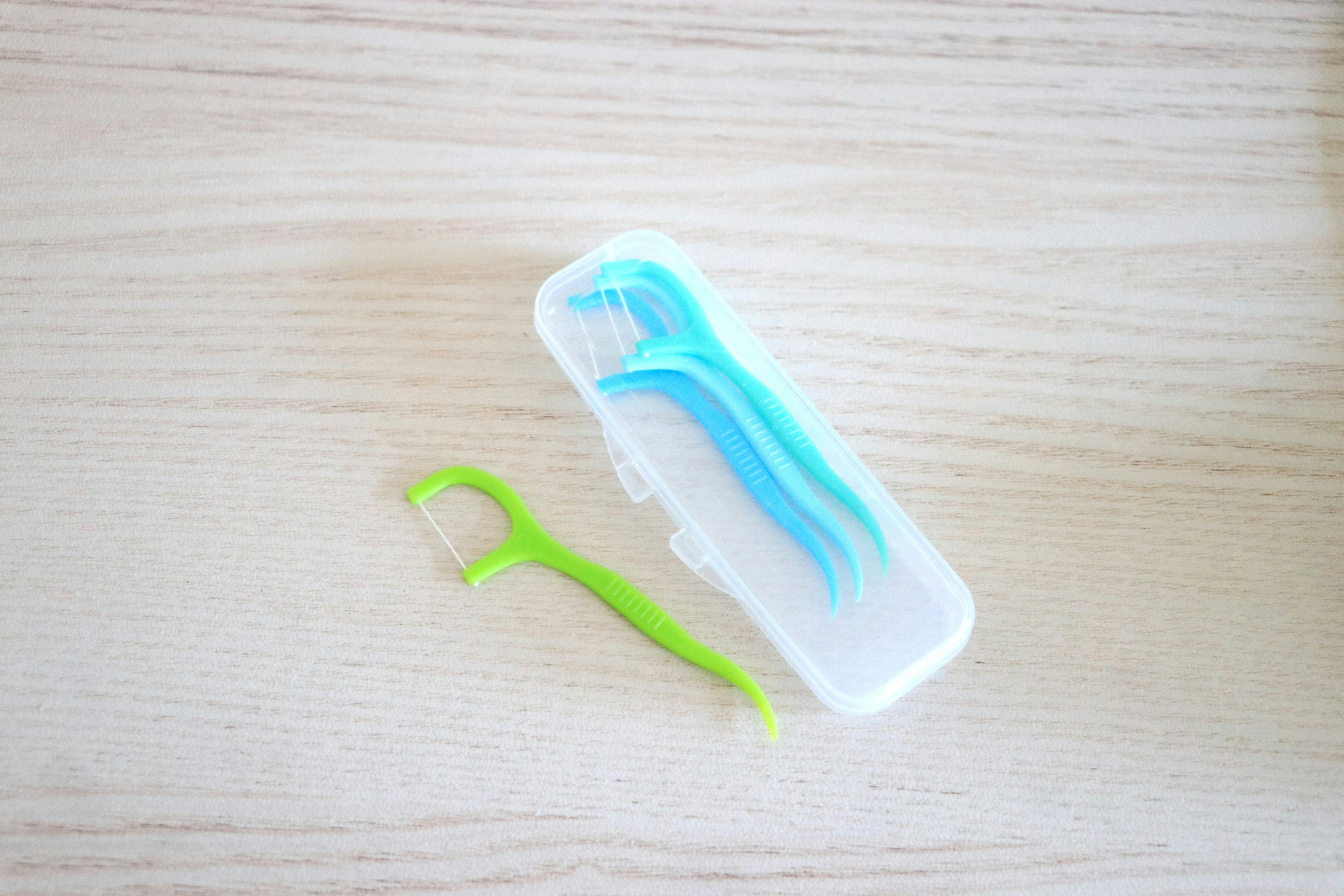 Sikat gigi interdental biru dan benang gigi hijau dalam kotak