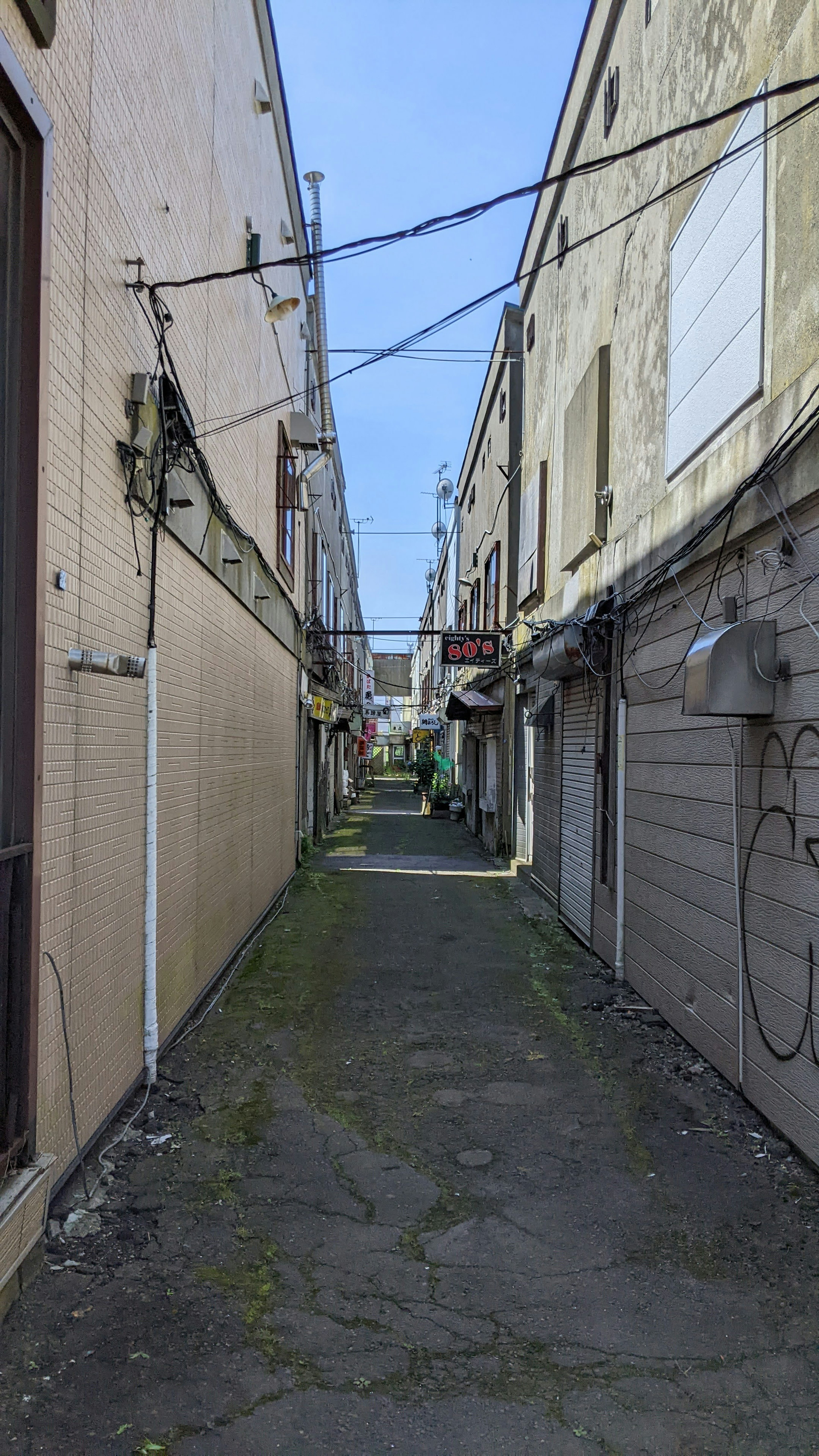 狭い路地の風景 両側に古い建物と電線