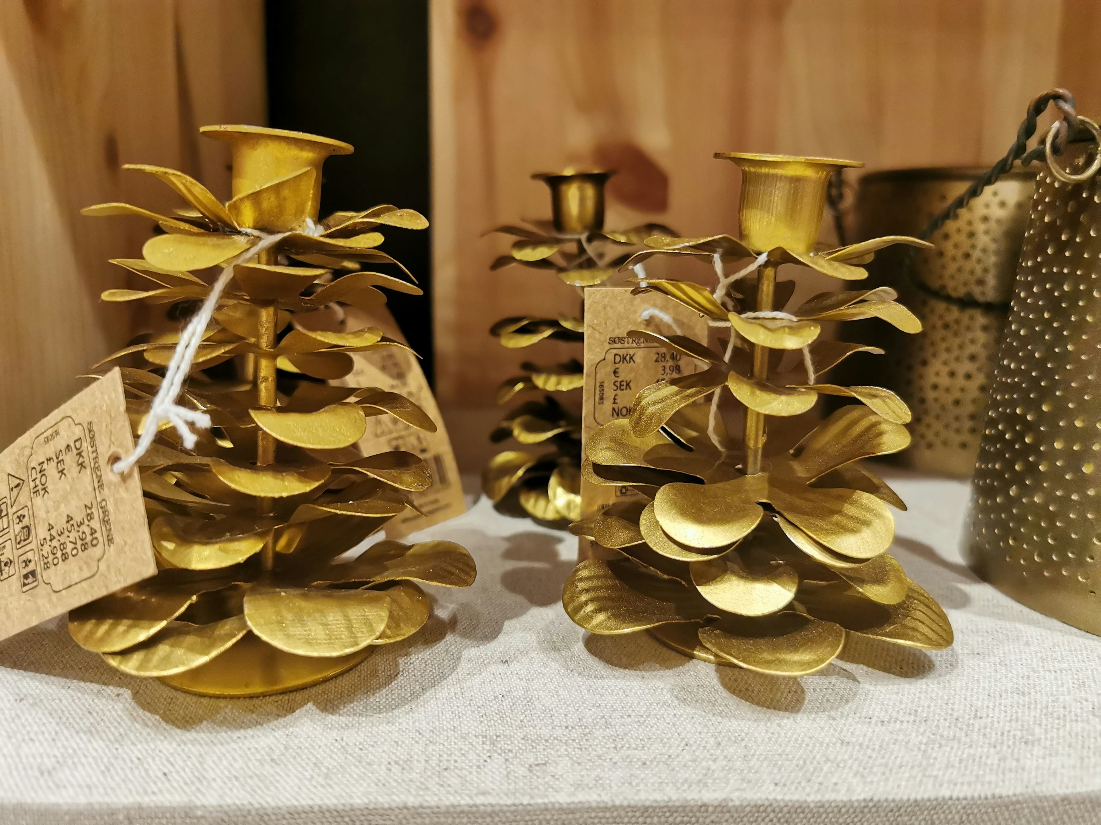 Two gold candle holders shaped like pine cones with decorative leaves