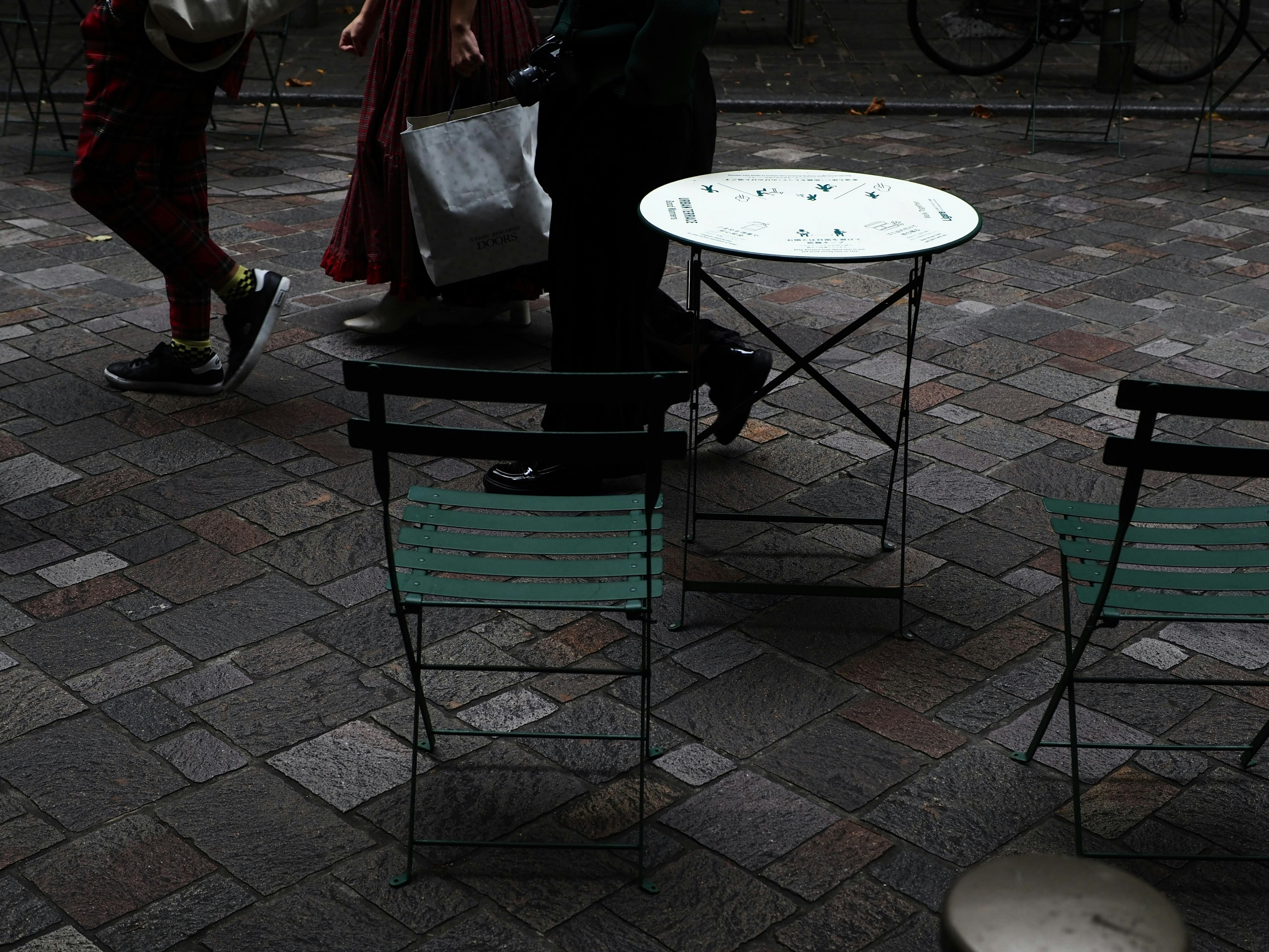 Scène d'un café avec une table et des chaises alors que des gens passent