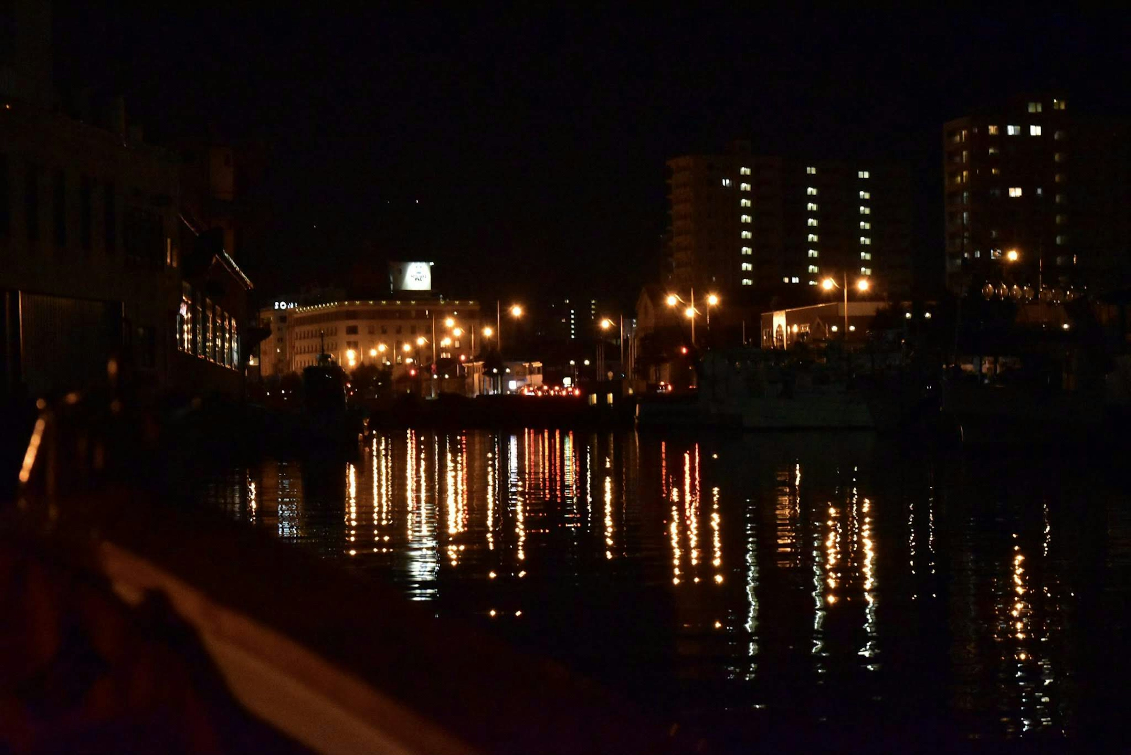 Stadtlichter und Gebäude, die sich nachts in einem Fluss spiegeln