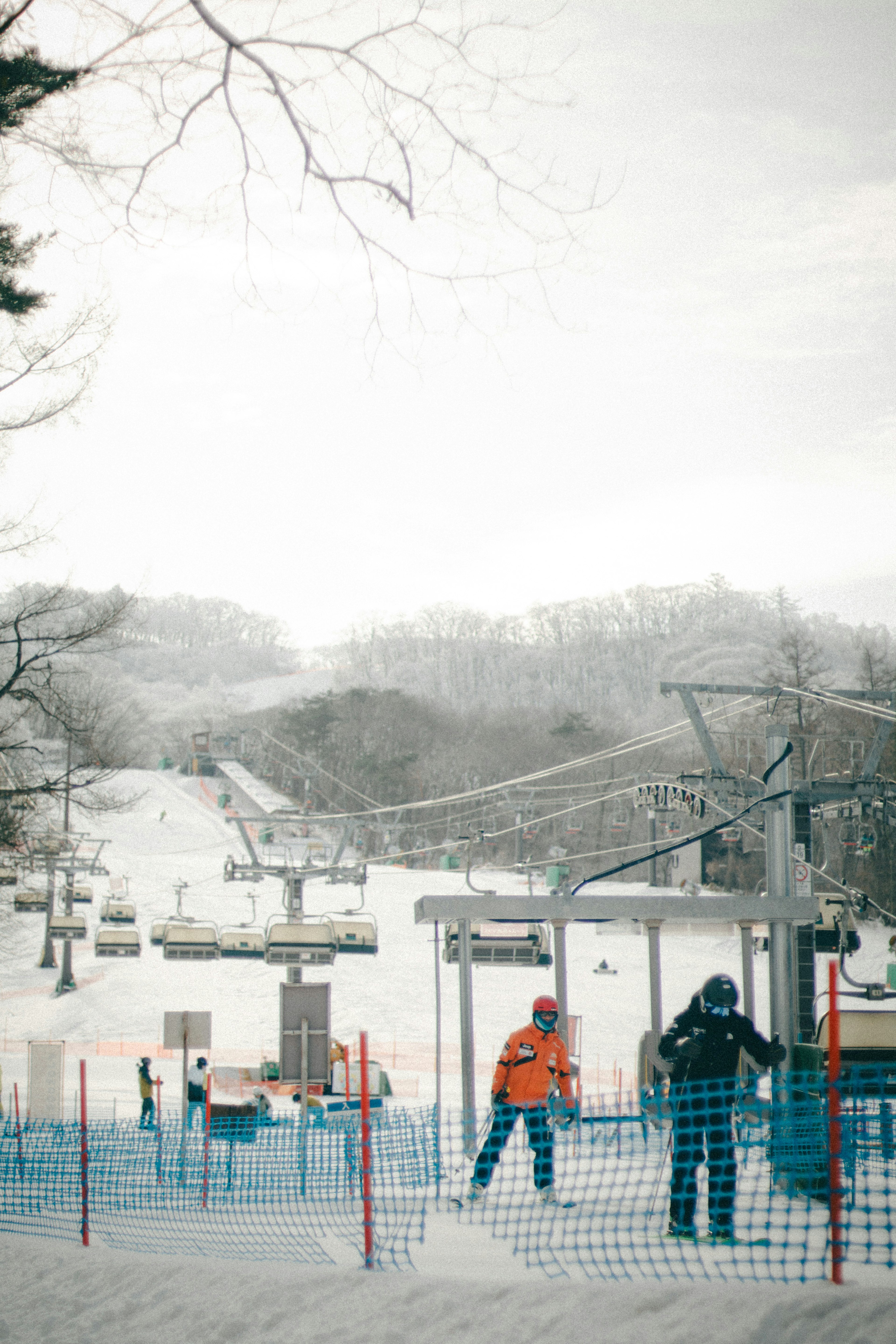 Two skiers waiting at a ski lift with a snowy landscape