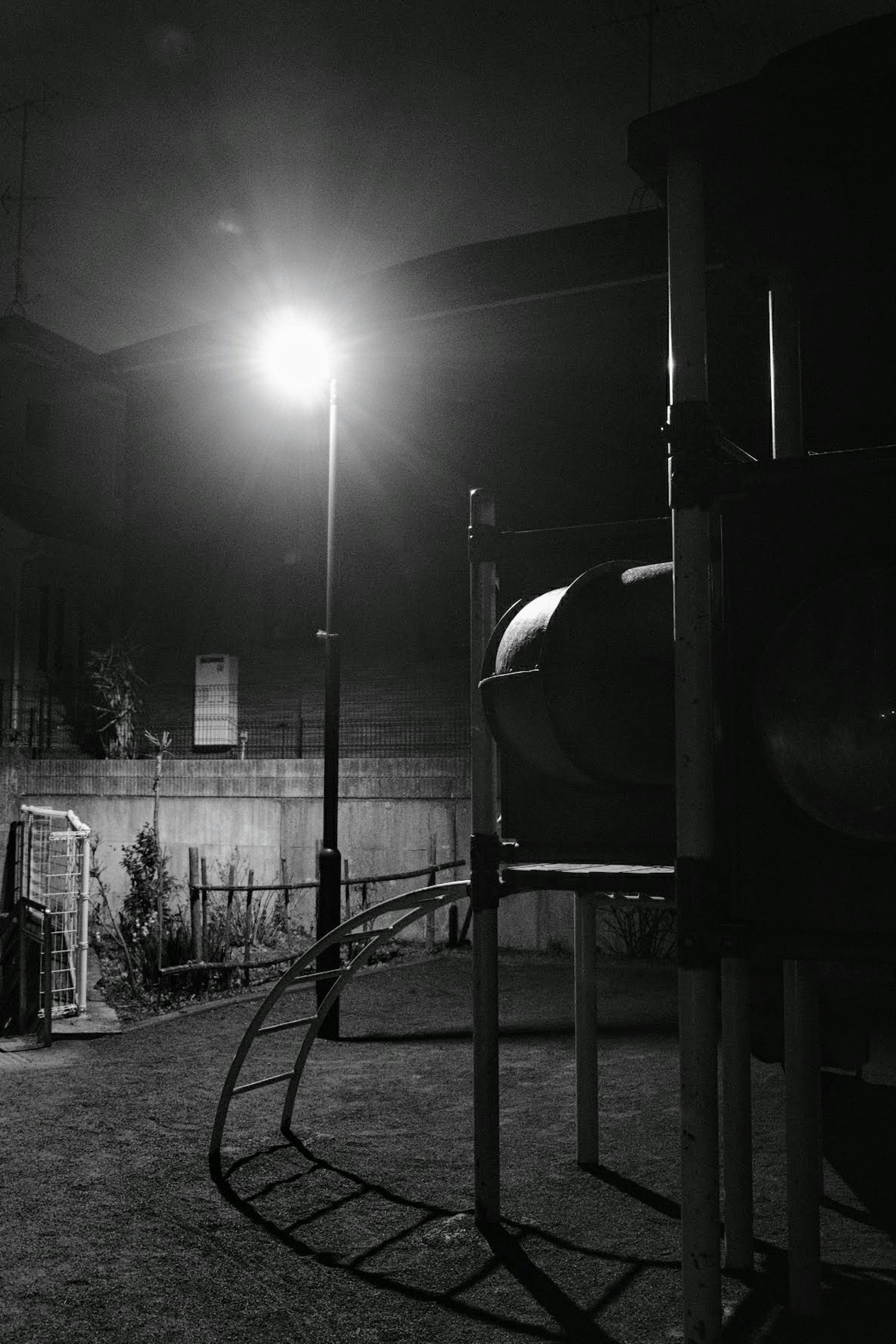 Nighttime playground featuring a slide and streetlight