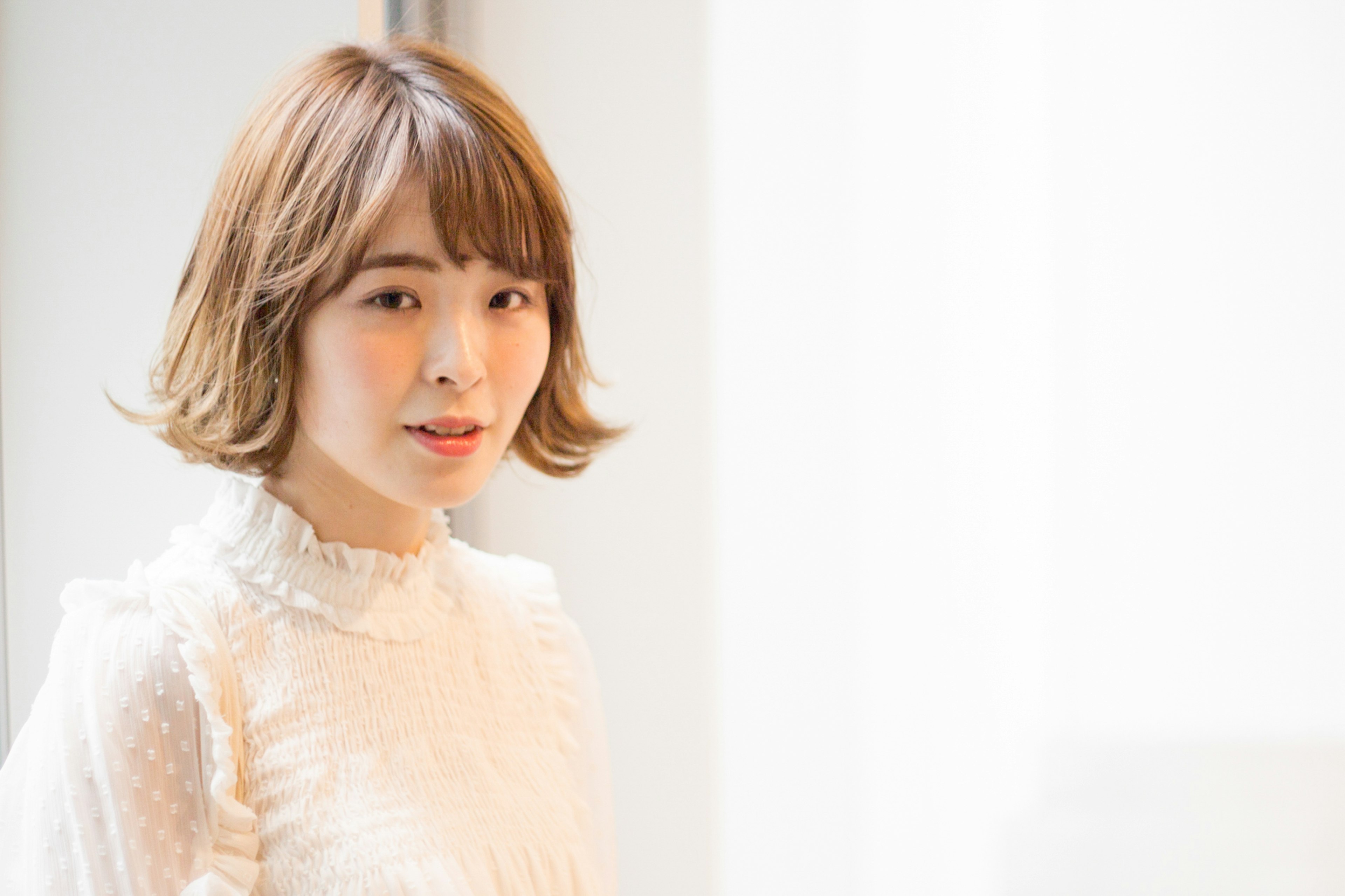 A woman with short hair standing in front of a bright white background