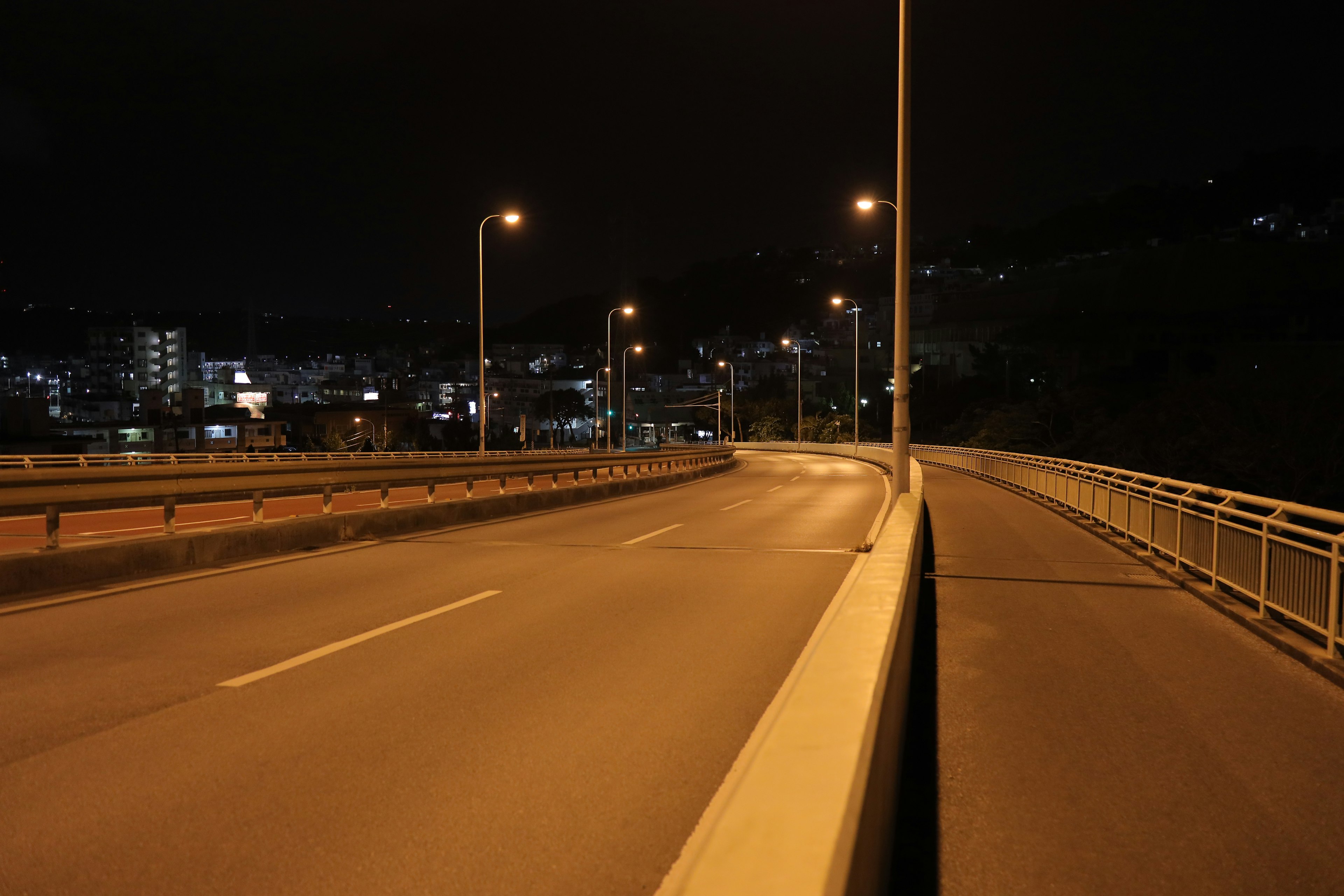 Nighttime view of a bridge with streetlights illuminating a dark road