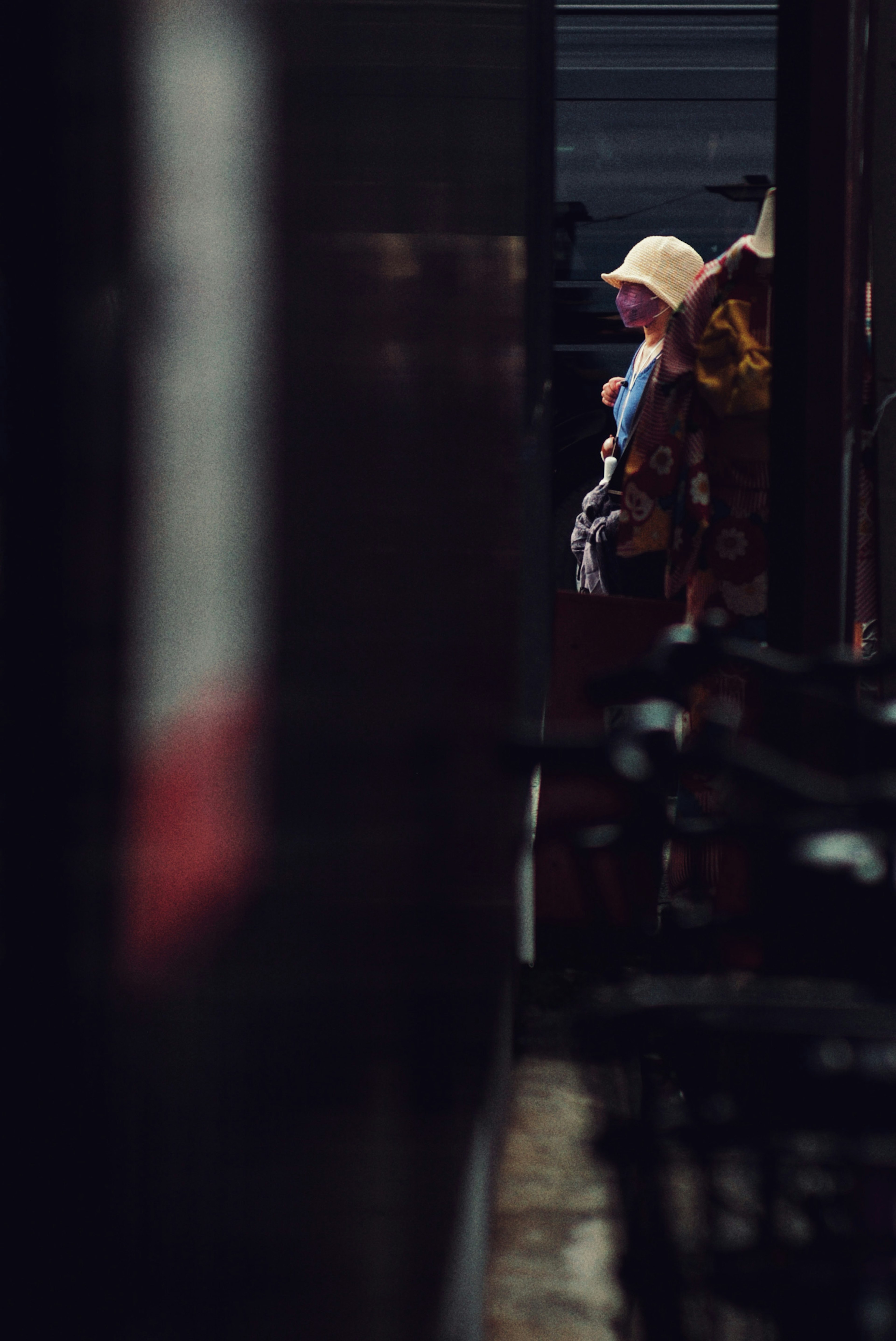 A person wearing a hat stands in a dimly lit passage