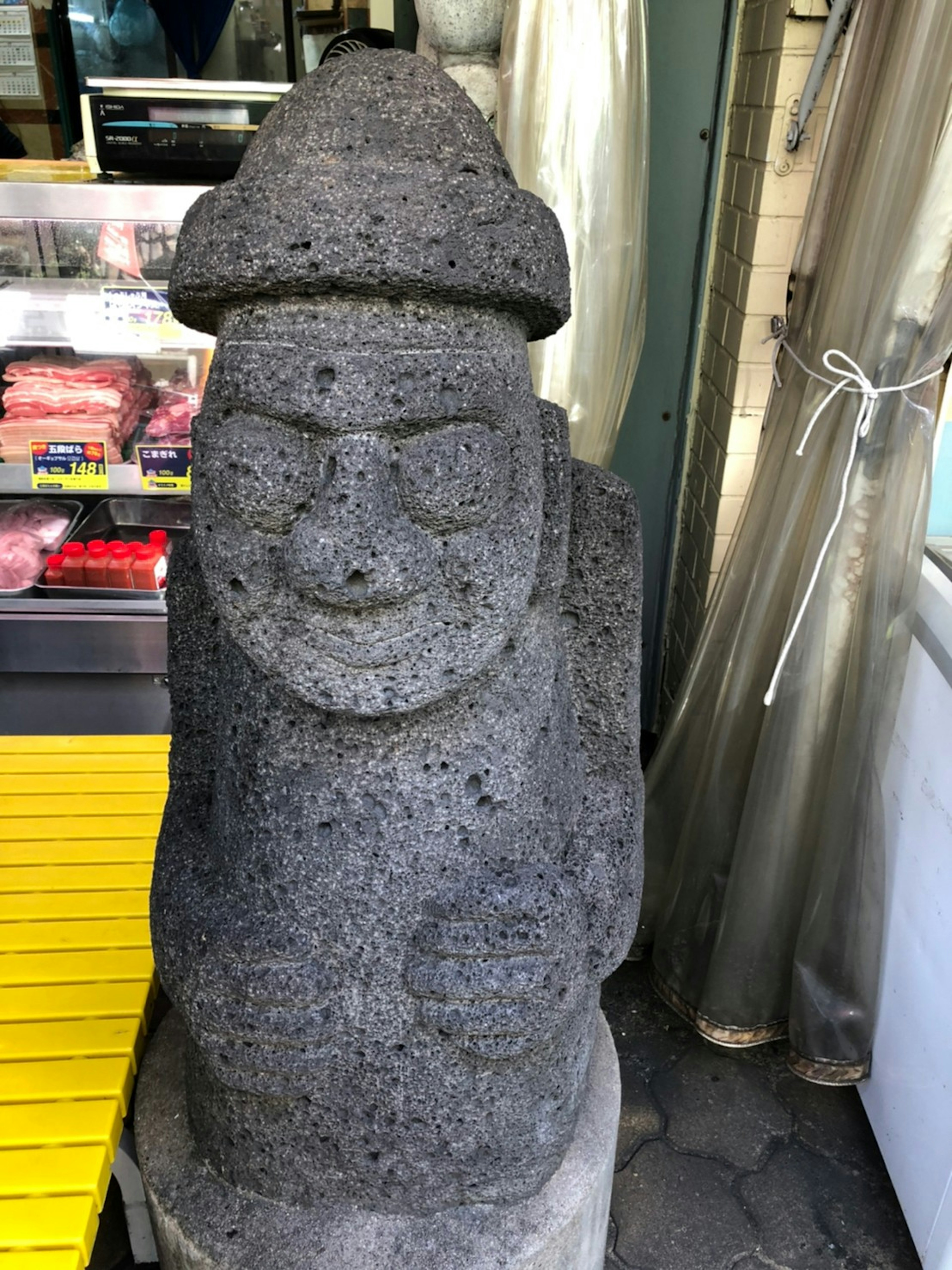 Statue en pierre avec un visage souriant et un chapeau