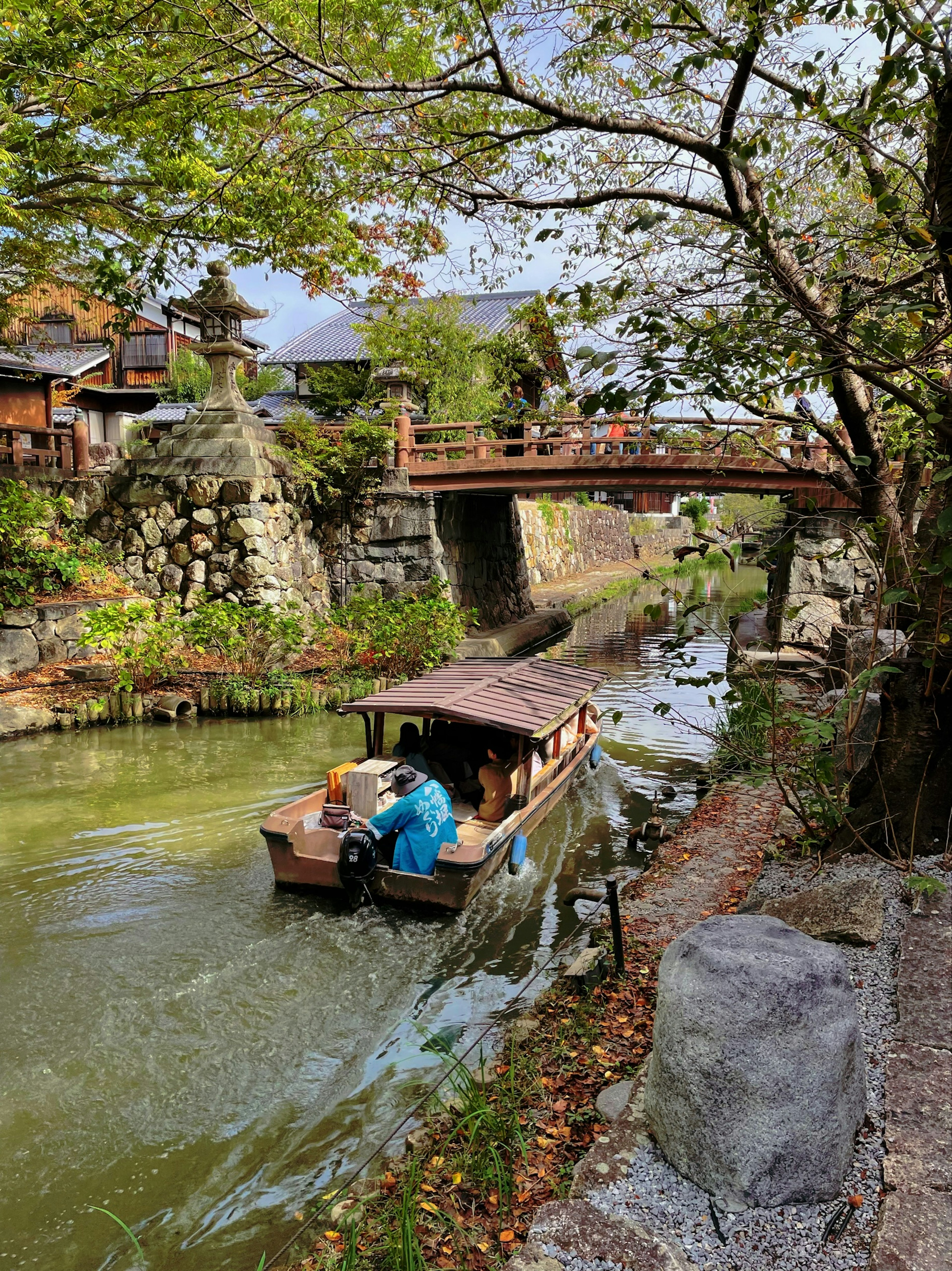 A small boat drifting on a river passing under a beautiful bridge