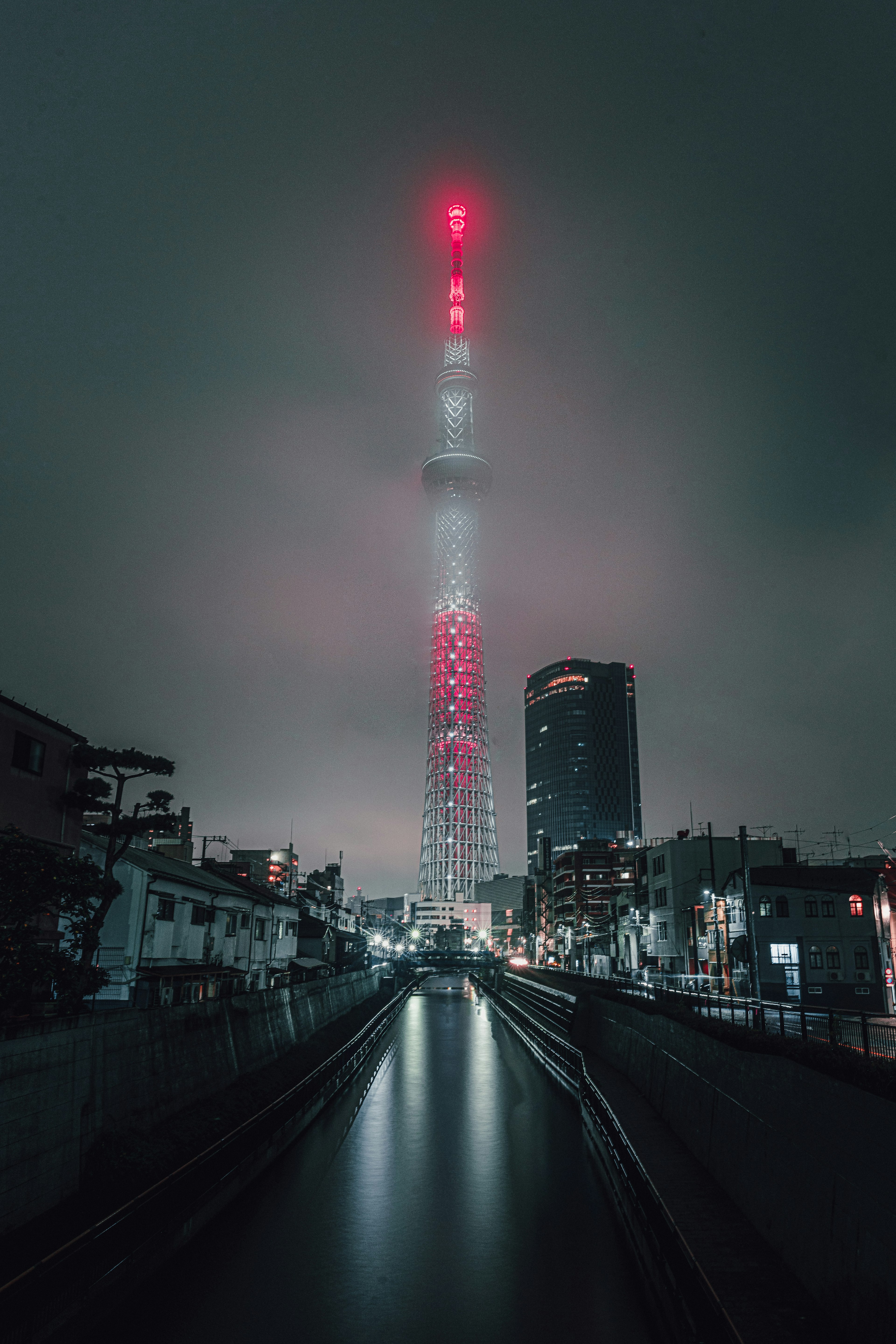 Tokyo Skytree towering through foggy night sky with illuminated red lights