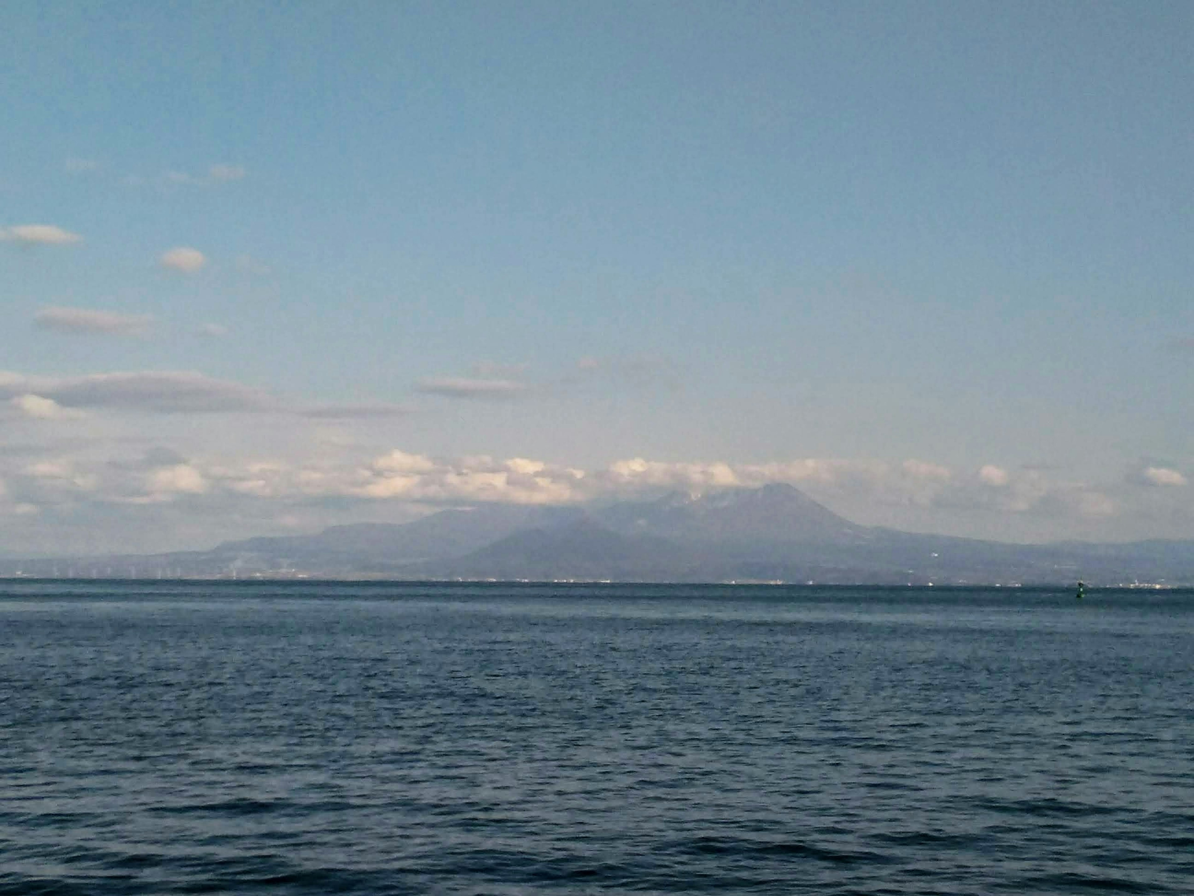 In der Ferne sichtbare Berge über einem blauen Meer unter einem klaren Himmel