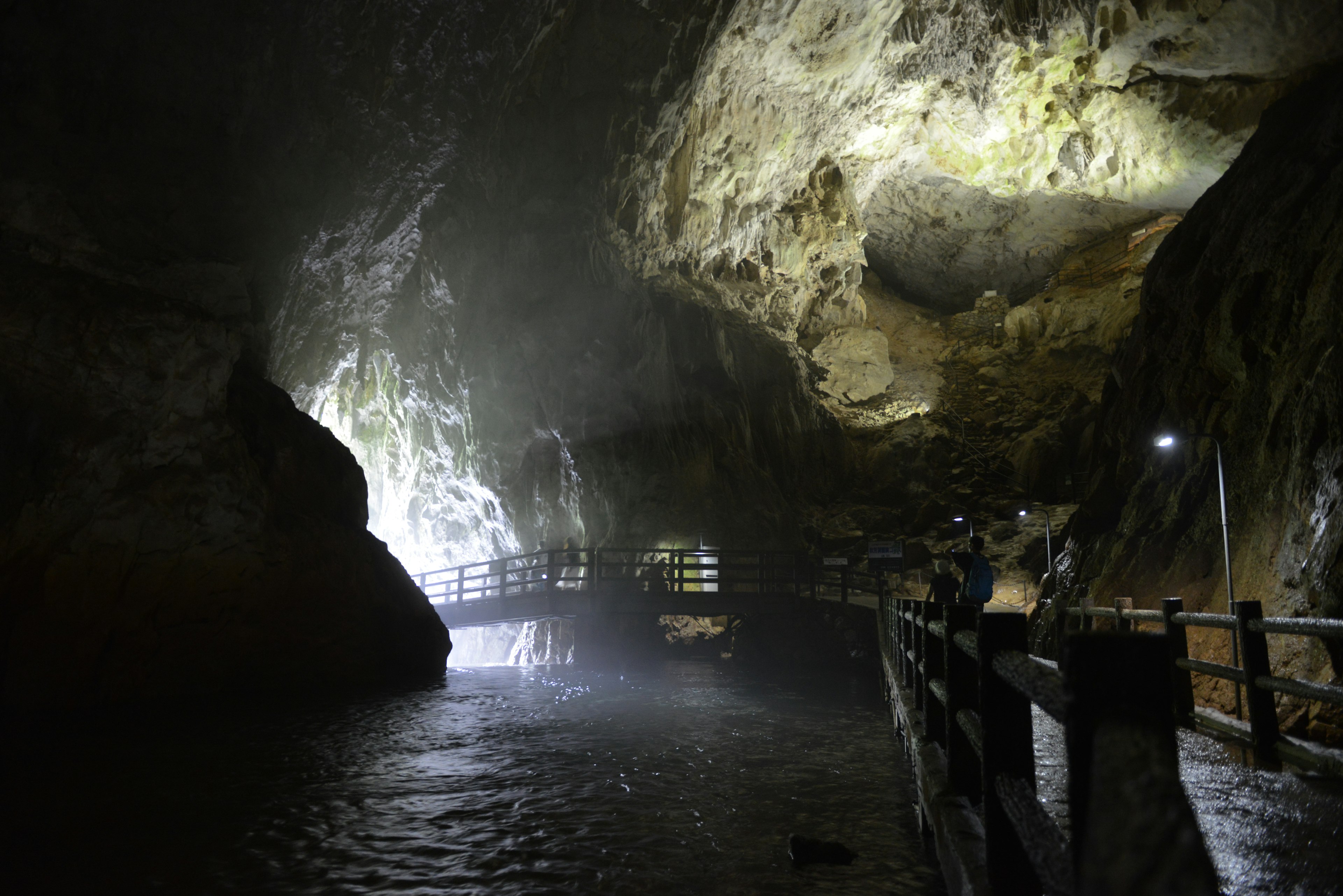 Interior oscuro de la cueva con pasarela de madera y reflejos en la superficie del agua