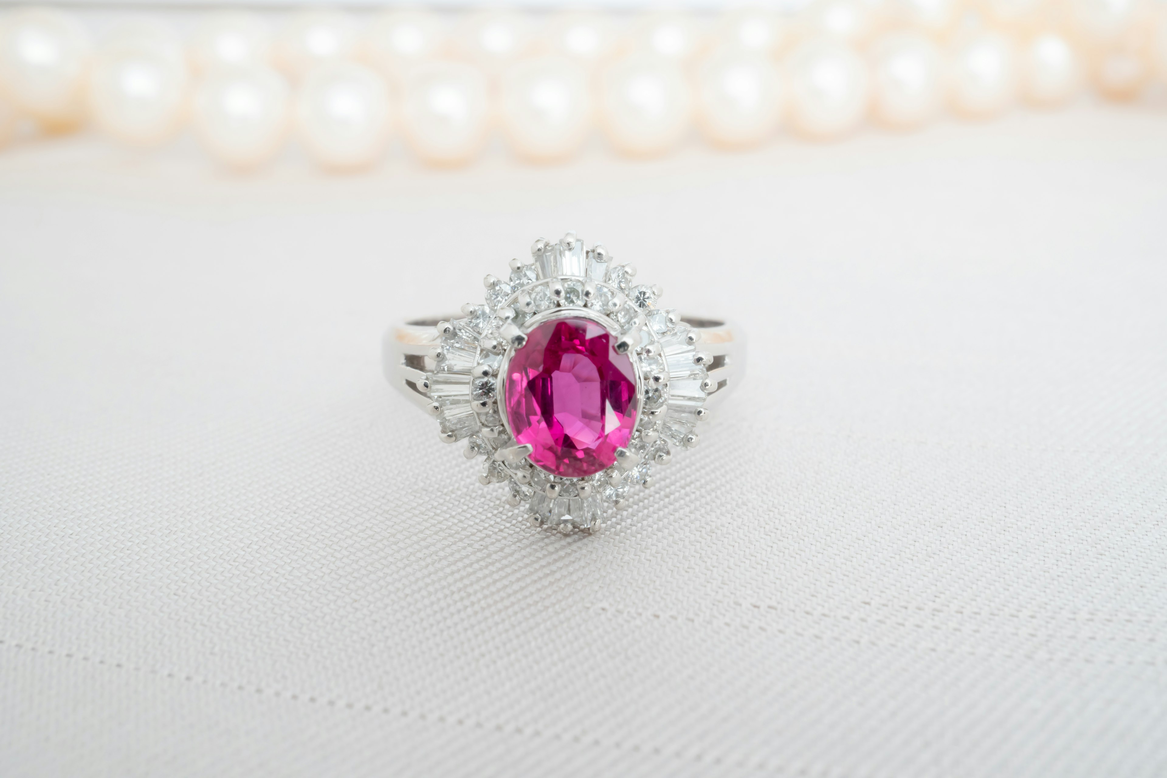 Schöner Ring mit einem zentralen rosa Edelstein und einer Perlenkette