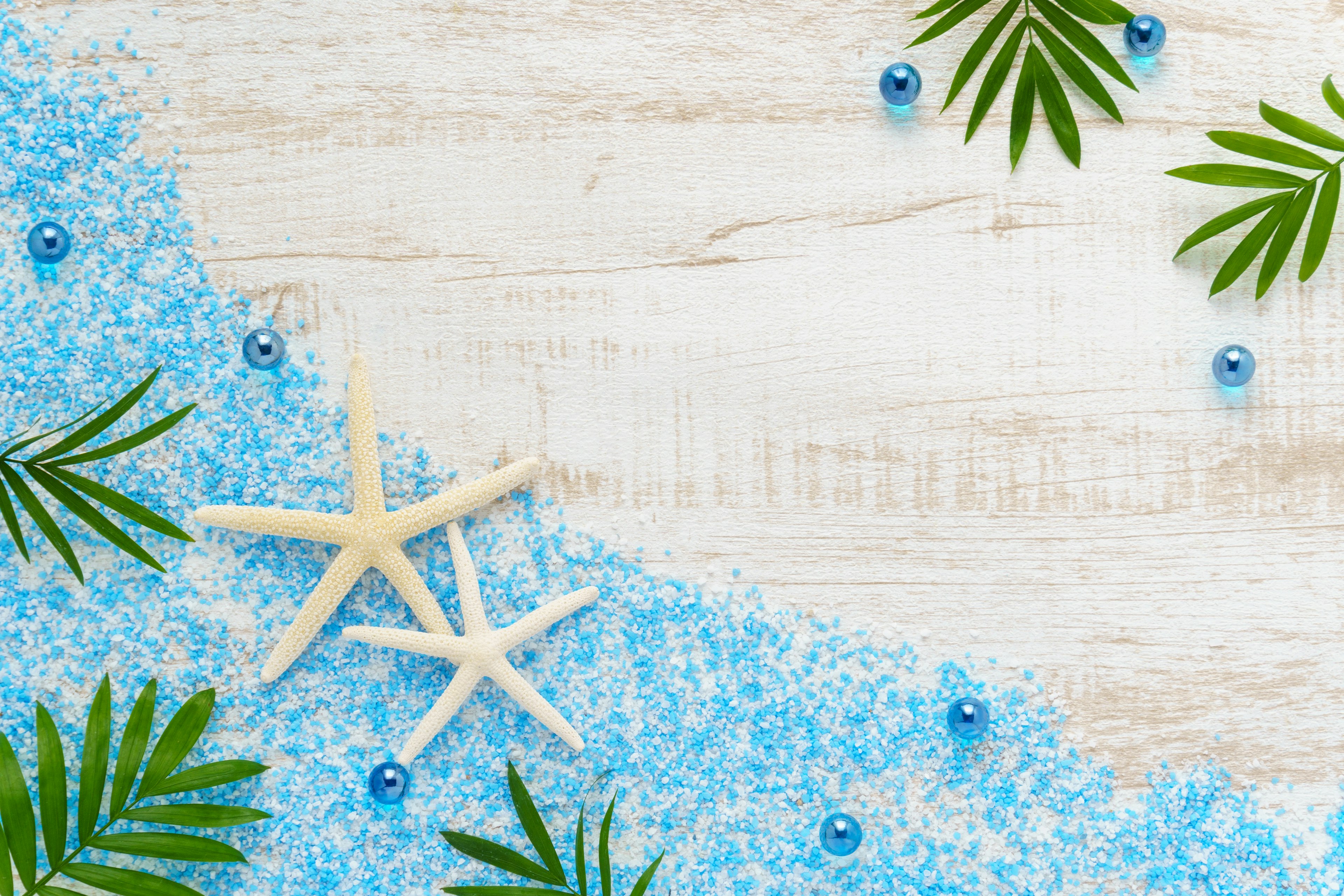 Beach-themed decoration with blue sand and starfish on a wooden surface