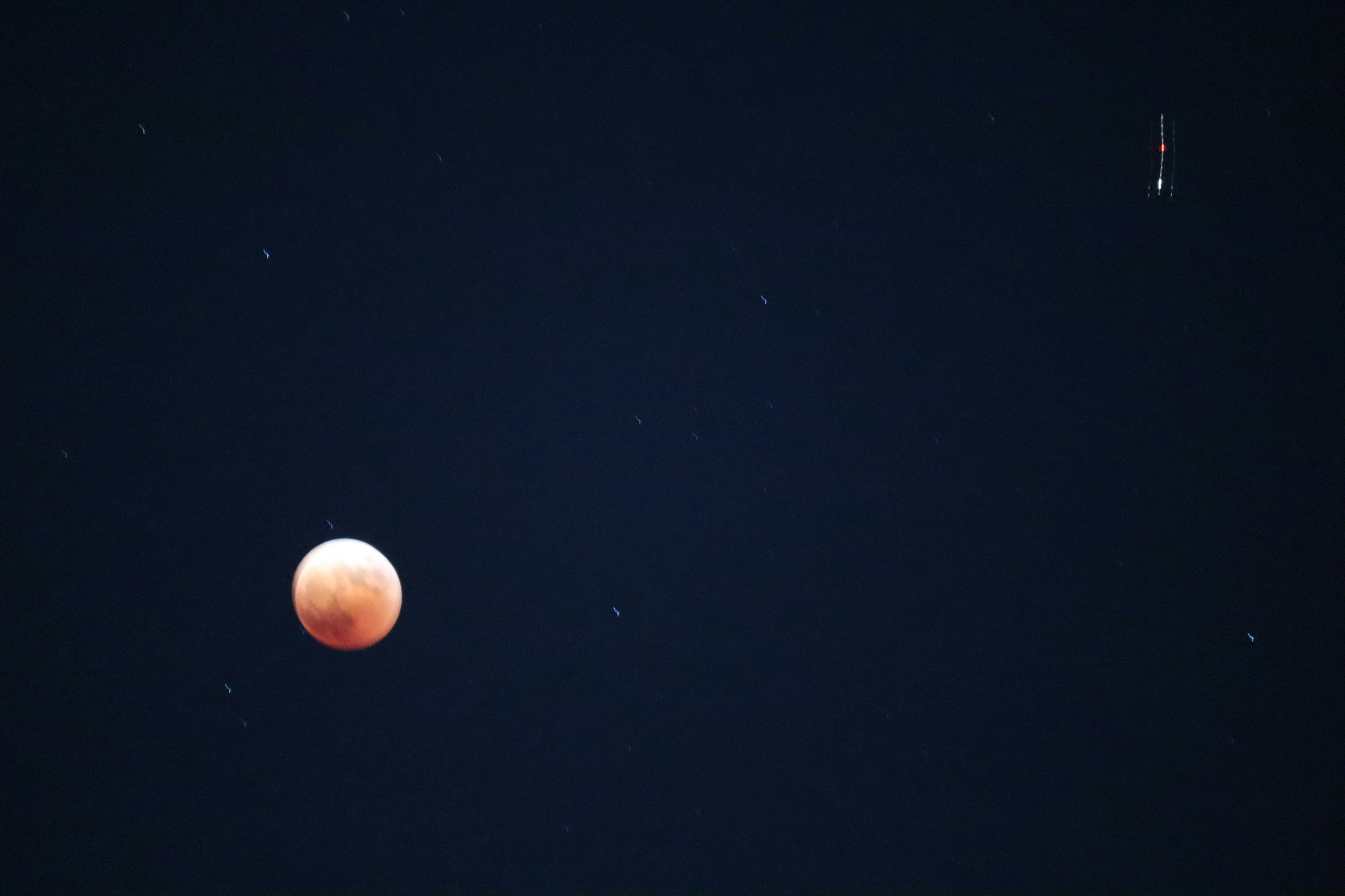 Una luna rossa contro un cielo scuro pieno di stelle