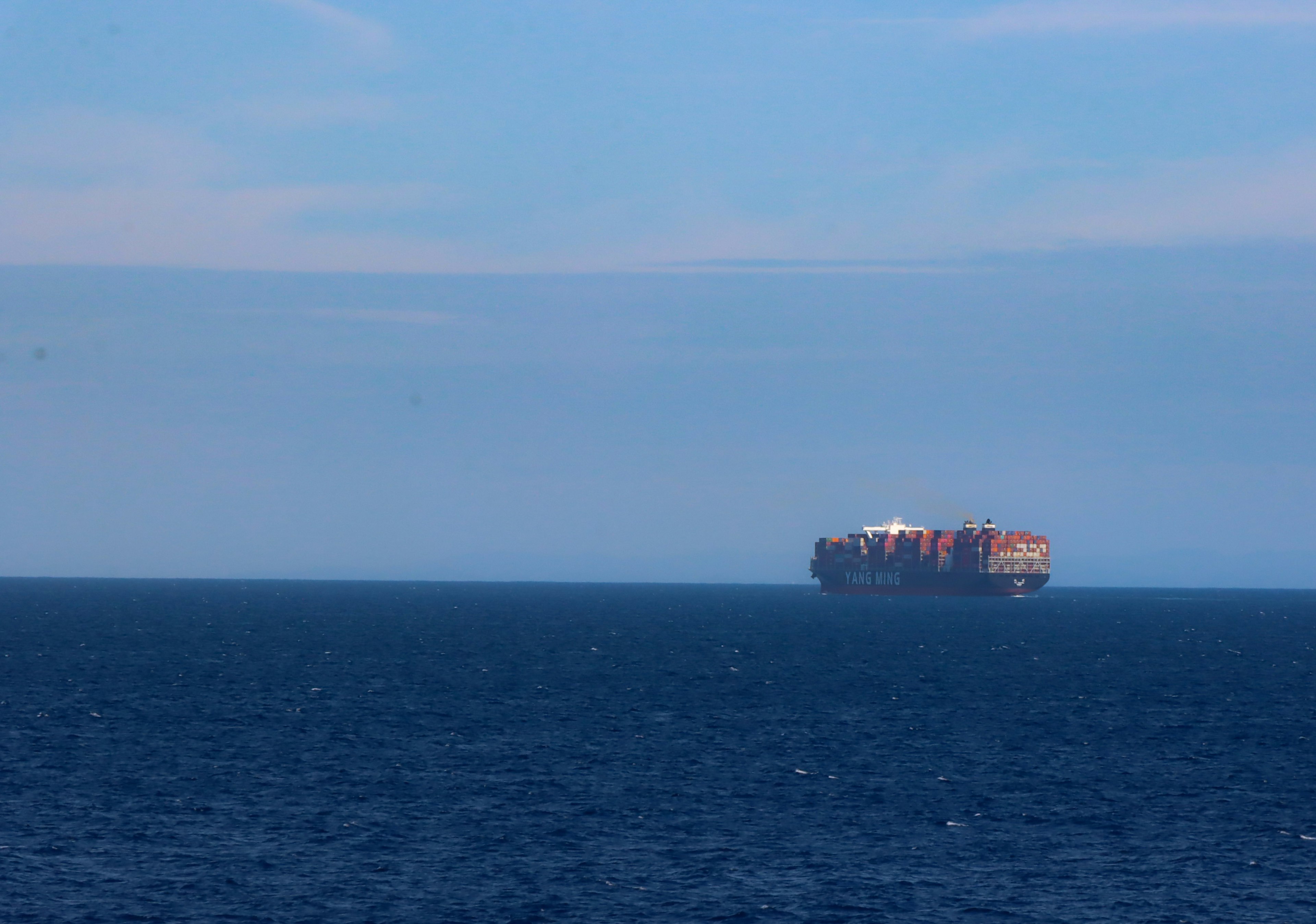 Ein großes Containerschiff, das in der Ferne auf einem blauen Meer schwimmt