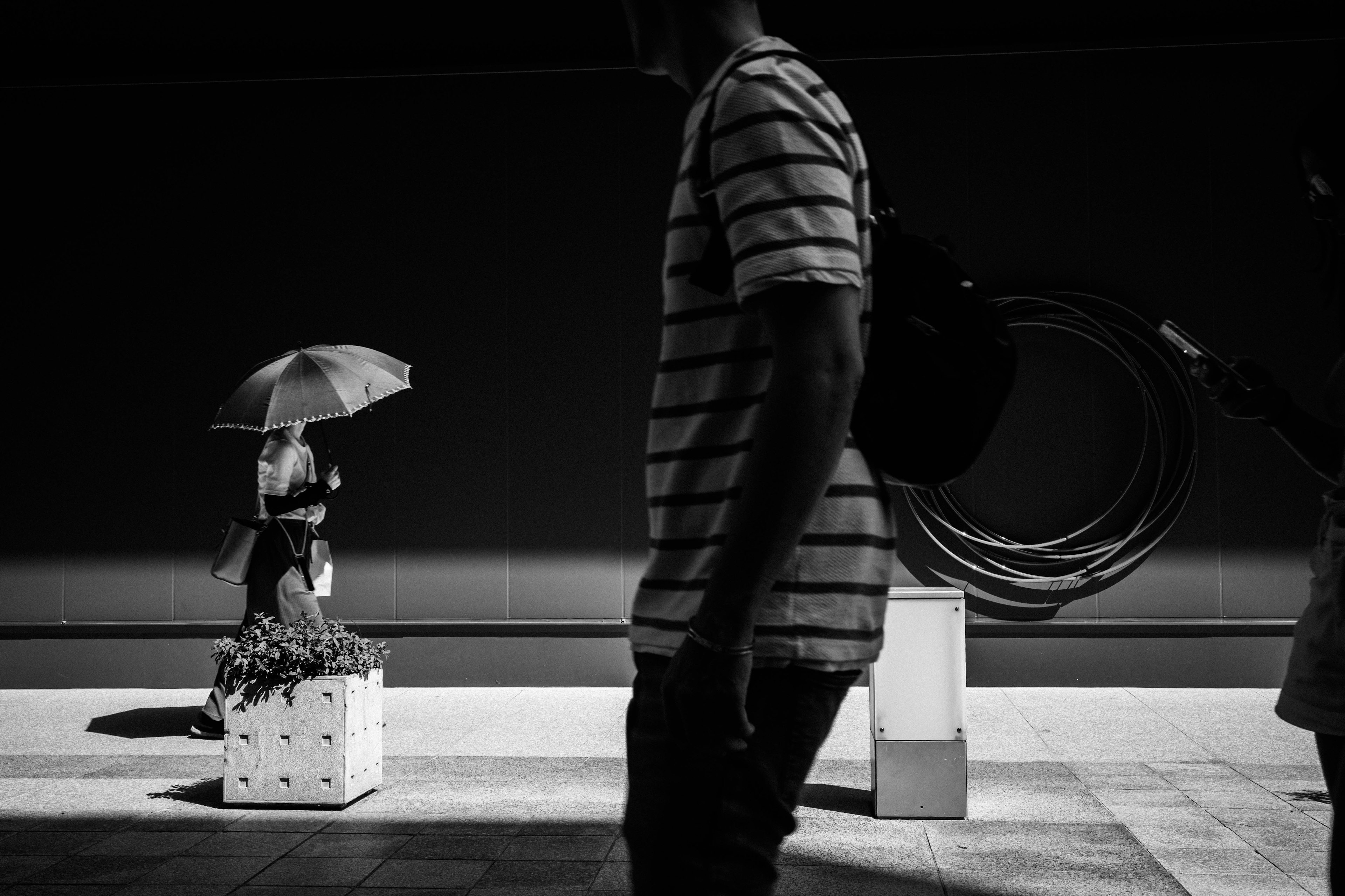 Silhouette of a man in a striped shirt and a woman holding an umbrella